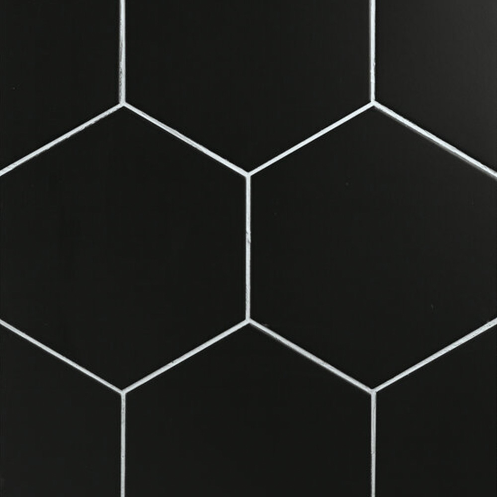 Home Hexagon - Black tiles feature a matte finish and a hexagonal shape, arranged with thin white grout lines to create a seamless geometric pattern. Their precise alignment contributes to a sleek, modern, and minimalist aesthetic.