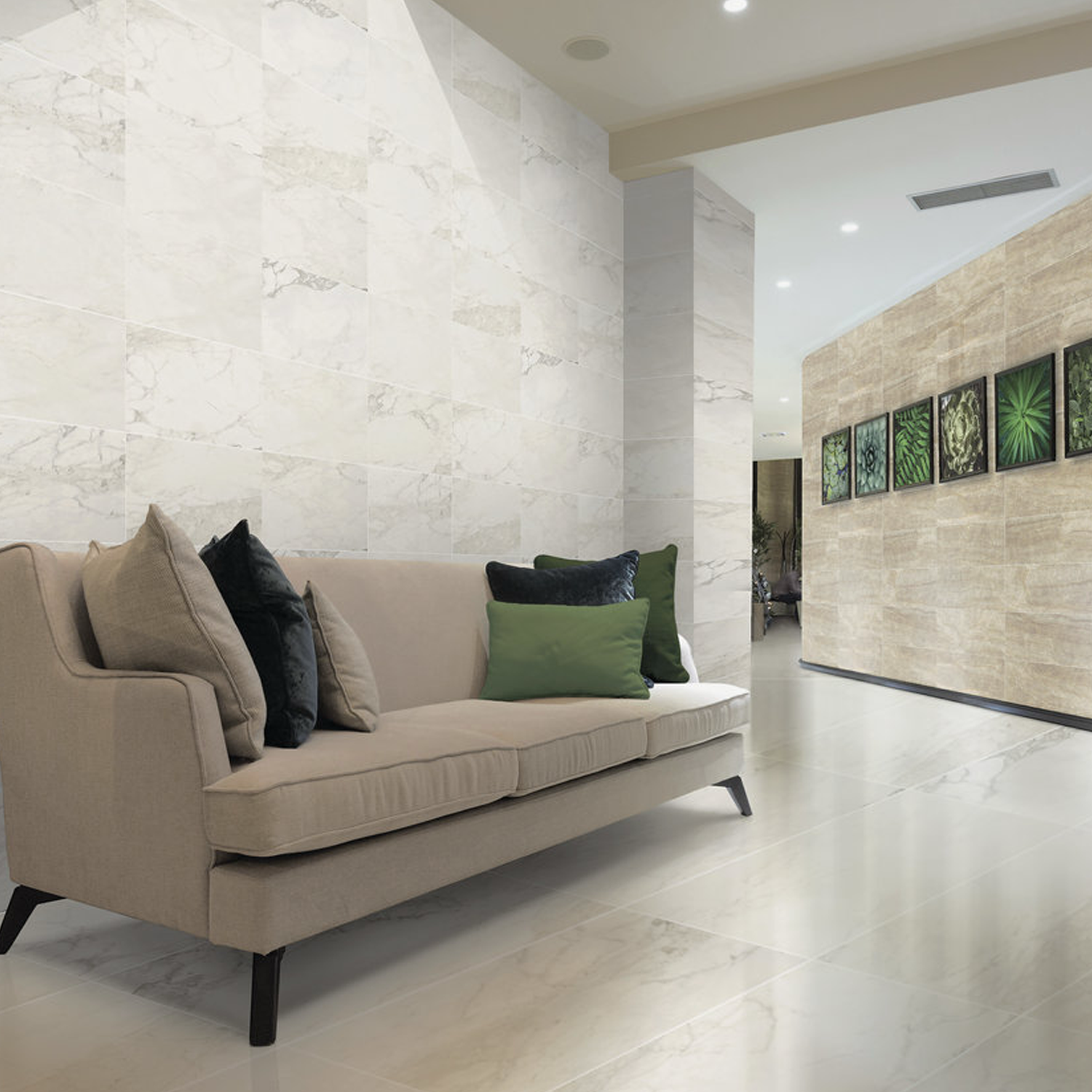 A modern living room featuring a beige sofa with several cushions, light-colored stone walls, and framed green leaf artwork arranged in a row on one wall is enhanced by the elegant white marble tile floors of Carrara Select 2.0.