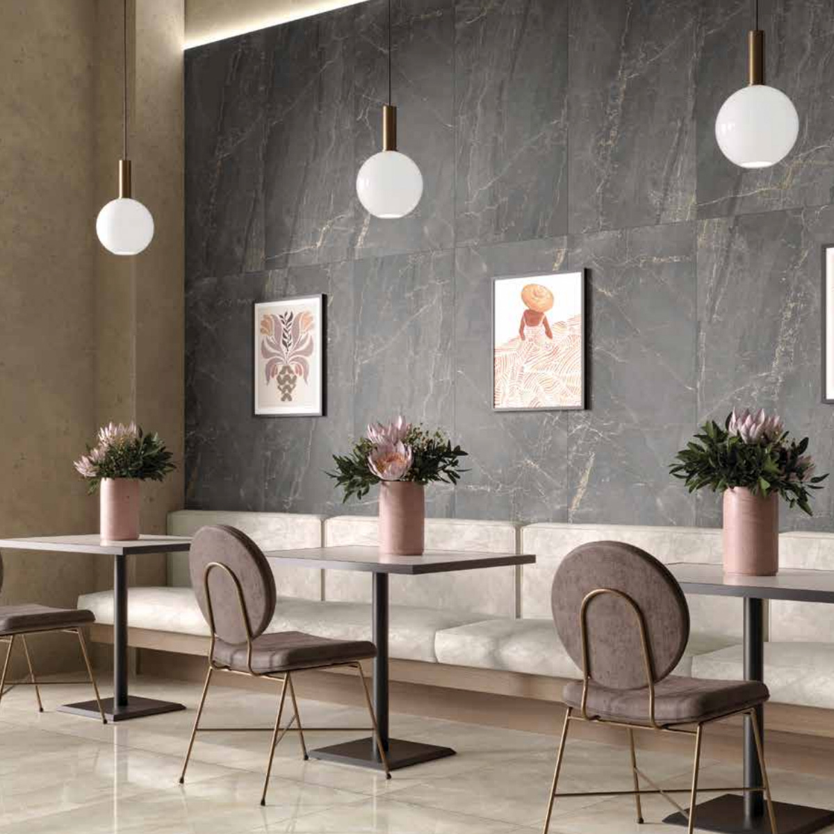 Modern café interior featuring Charme - Black gray marble walls, three hanging globe lights, beige bench seating, small tables topped with pink vases of flowers, gray chairs, and framed artwork adorning the wall.