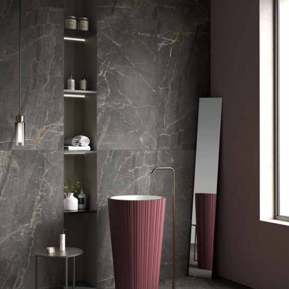 Modern bathroom featuring Charme - Black marble walls, a tall oval mirror, a striking red freestanding sink, open shelves displaying towels and decor, a round side table, and a tall window flooding the space with natural light.