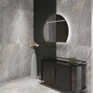 Modern entryway featuring Charme - Grey marble walls and floor, a round backlit mirror above a sleek black console table, and a tall white vase with dried flowers. A small handbag rests on the console.