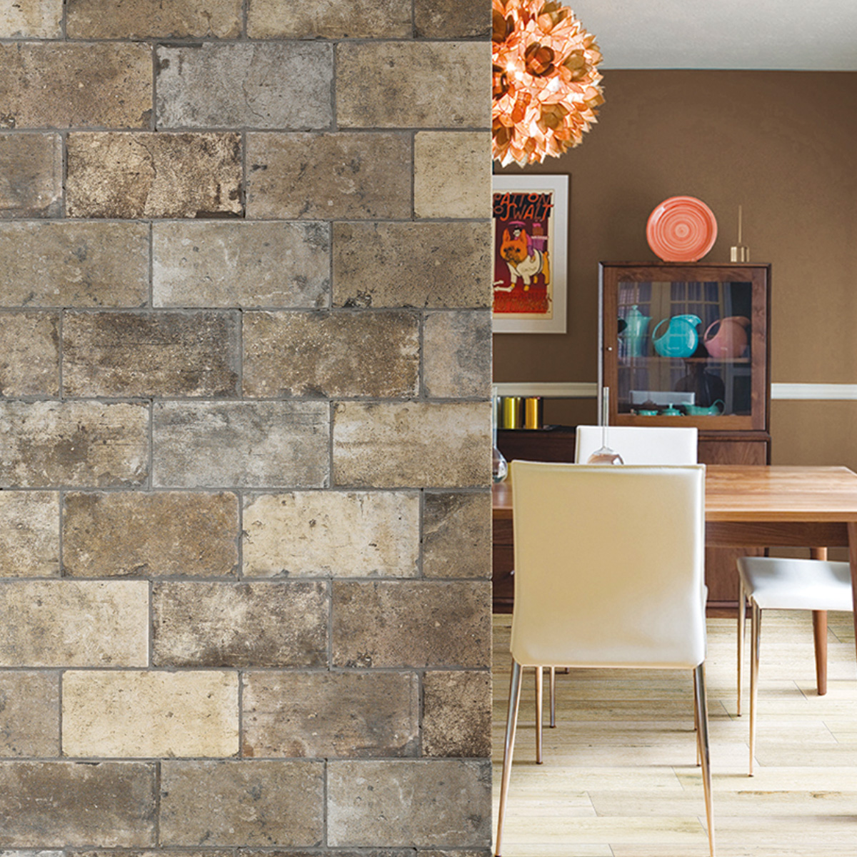 Close-up of stone-look brick wall tiles in mixed brown, charcoal, and sandy beige tones in a running bond pattern, with a mid-century modern dining room visible in the right half featuring a wood table, white chairs, a wood display cabinet, and a copper floral pendant light.