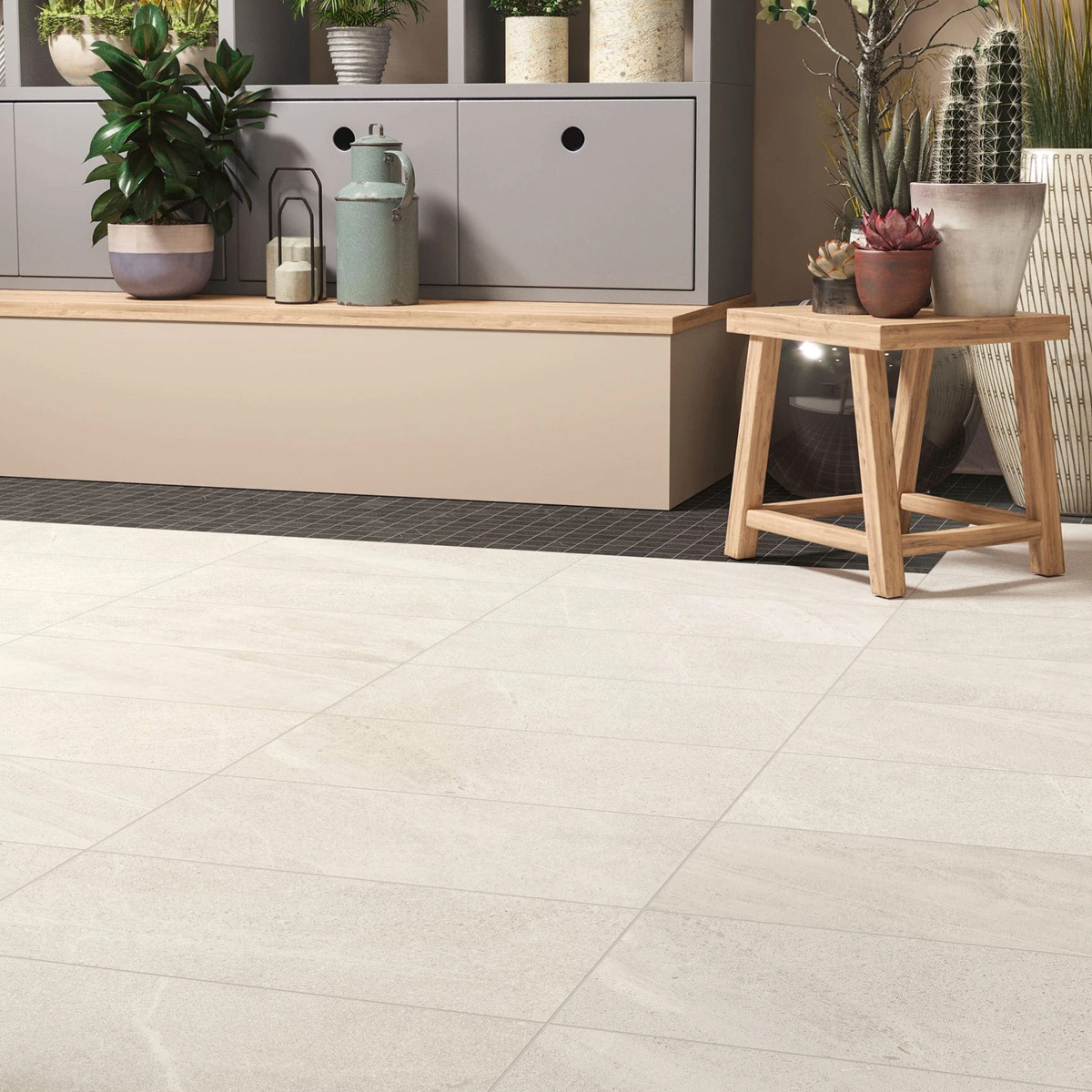 A modern, cozy interior space featuring Outland - Pure light-colored tiled flooring, complemented by a wooden bench, gray storage cabinets, potted plants, and a small wooden side table adorned with succulents.