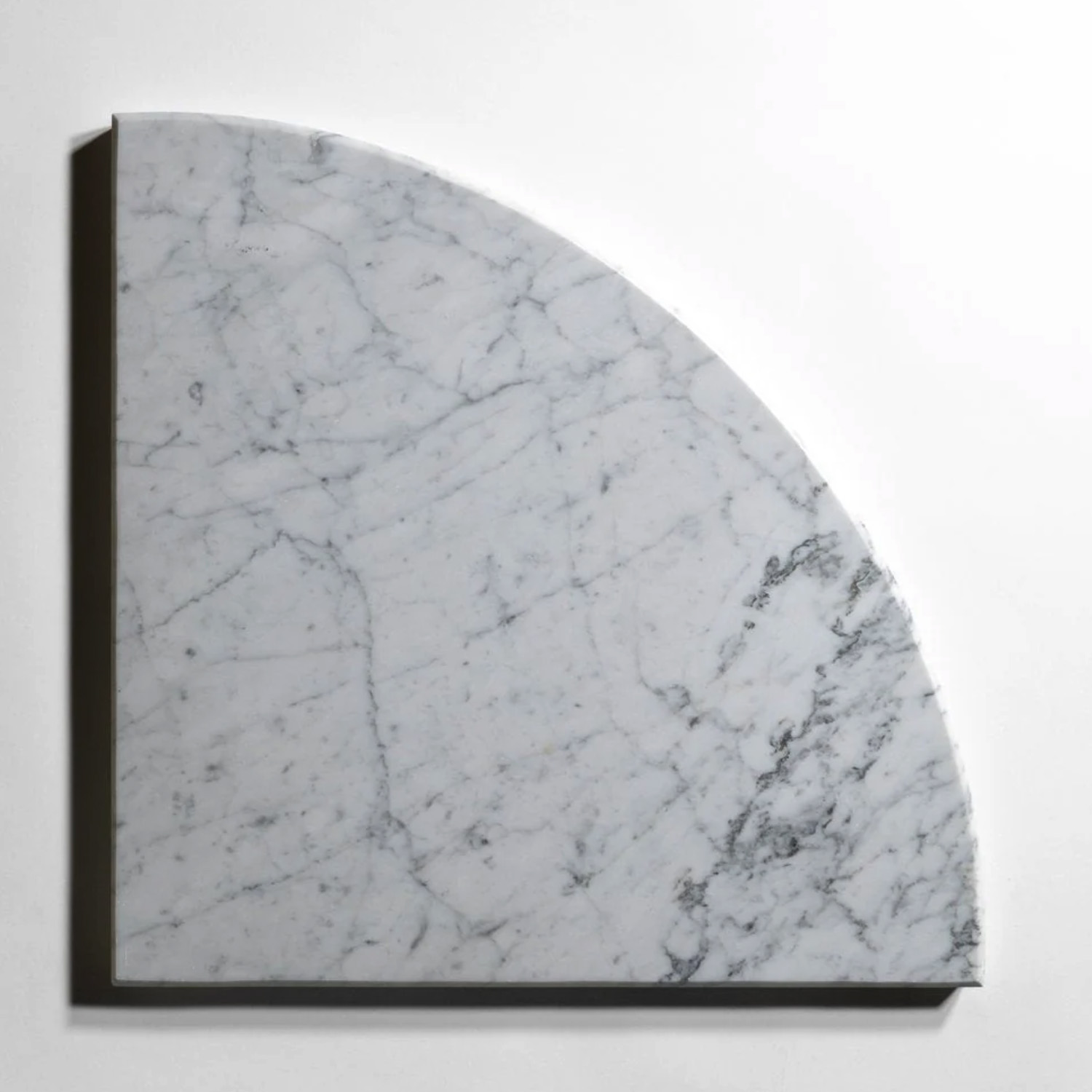 A quarter-circle Bath Accessories (Bevel Seat) - Venatino Carrara slab of white marble with elegant gray veining lies flat against a white background, casting a subtle shadow along its beveled straight edges.
