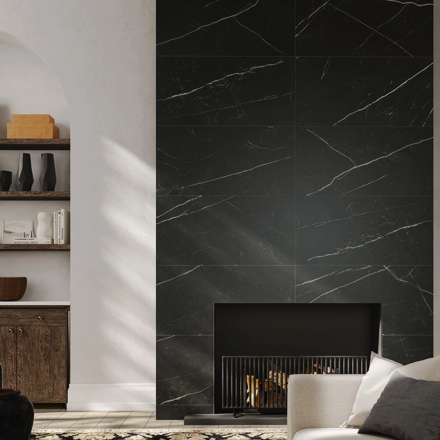 Modern living room featuring a fireplace clad in Beyond Calacatta - Black marble, complemented by a metal grate and dark shelves displaying books and decorative items. Light-colored walls and part of a cream sofa are illuminated by natural sunlight.