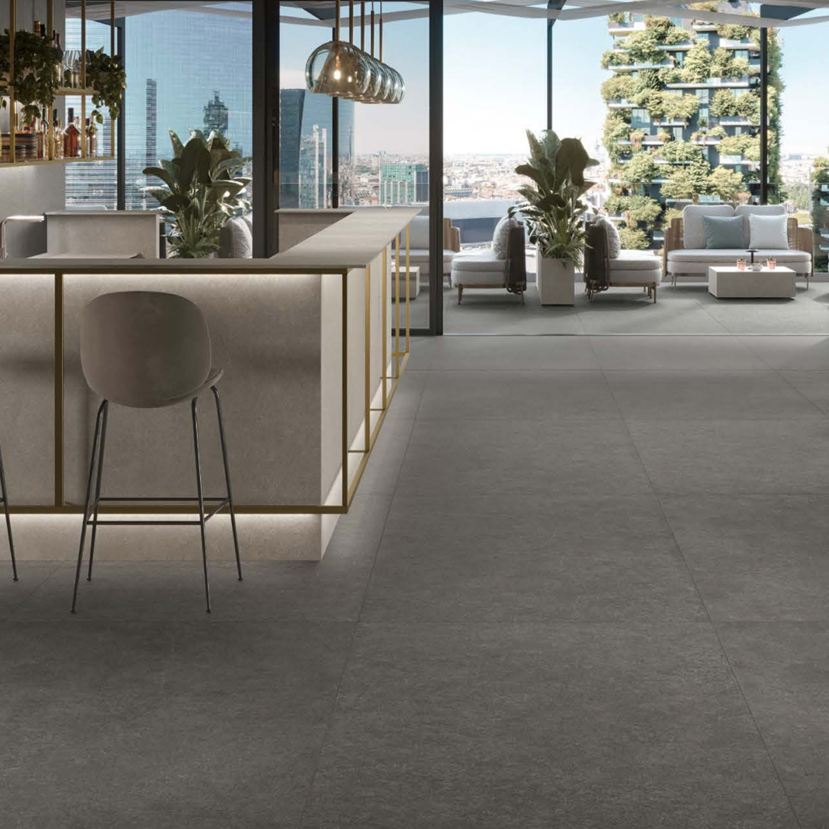 Modern indoor bar area featuring a Boost Mineral - Tarmac marble counter, high stools, potted plants, and floor-to-ceiling windows overlooking a cityscape and outdoor seating area with greenery in the background.