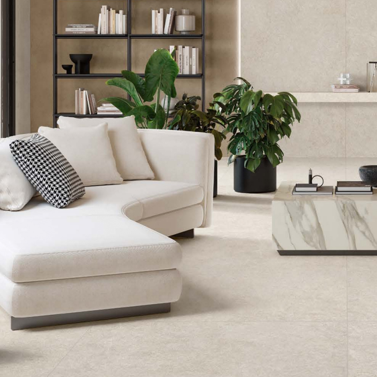 Contemporary living room featuring the Boost Mineral - White sectional sofa, accented with black and white pillows, green potted plants, a marble coffee table, and a black metal bookshelf against beige walls and flooring for a modern and minimalistic aesthetic.