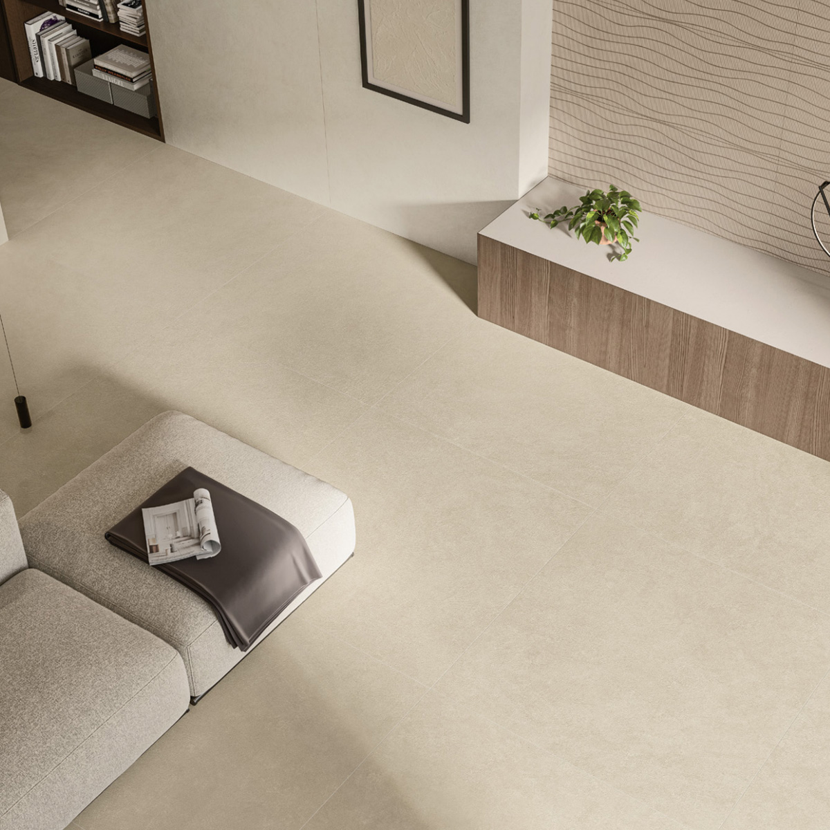 Minimalist living room featuring a light beige tiled floor, a gray couch with a magazine and blanket, built-in shelves, a low cabinet adorned with Boost Natural Pro - Oat, and neutral decor.