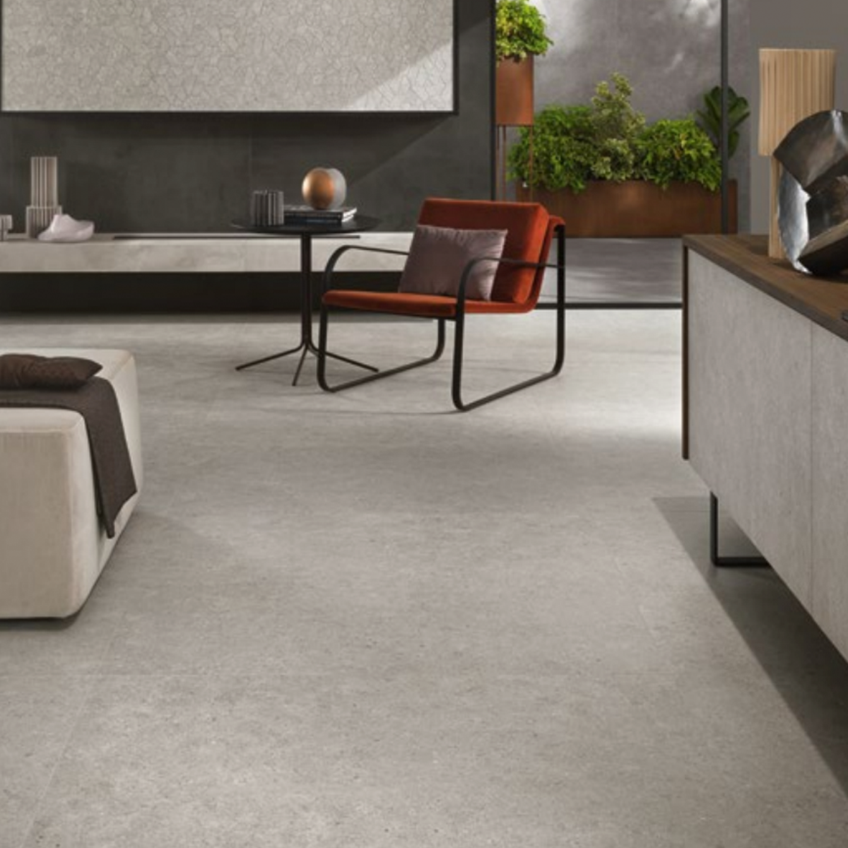Modern living room with a grey sofa, orange accent chair, wall art, plants, and minimalist decor in neutral tones. The clean, contemporary look is enhanced by marble-look Boost Stone - Pearl flooring and sleek furniture.