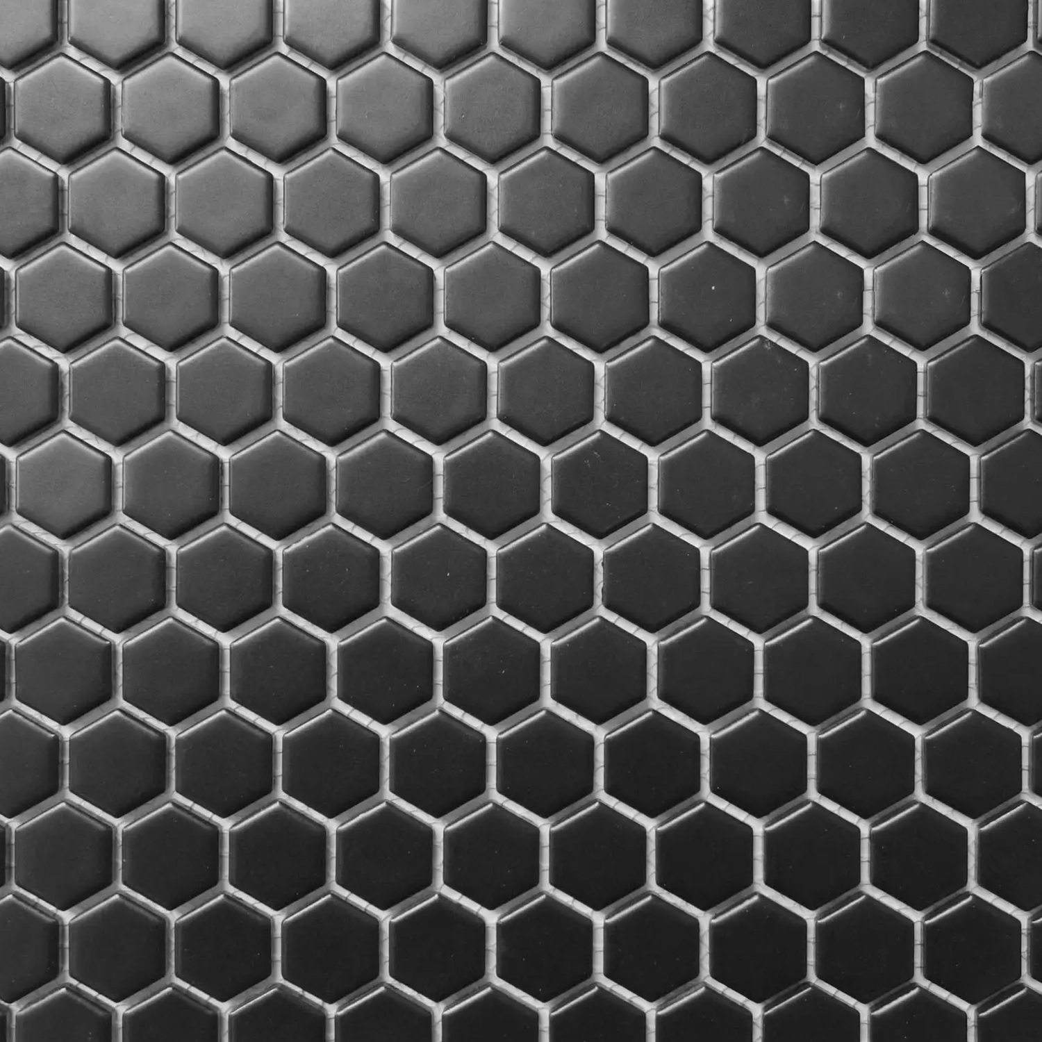 A close-up of a surface featuring CC Mosaics - Black tiles arranged in a honeycomb pattern.
