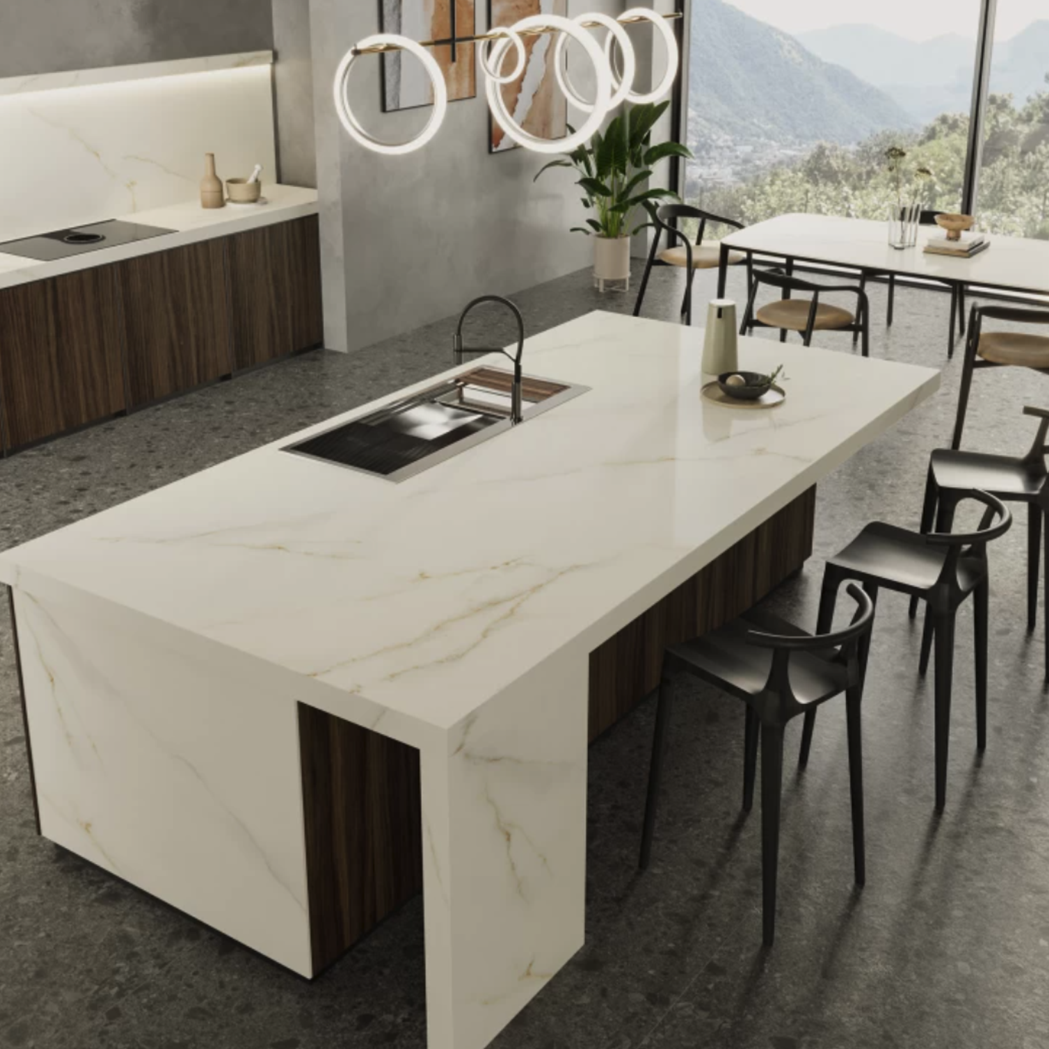 Modern kitchen featuring a spacious Calacatta Apuano marble island, black chairs, pendant lights, built-in sink, potted plant, and dining table. Expansive windows offer a scenic mountain view.