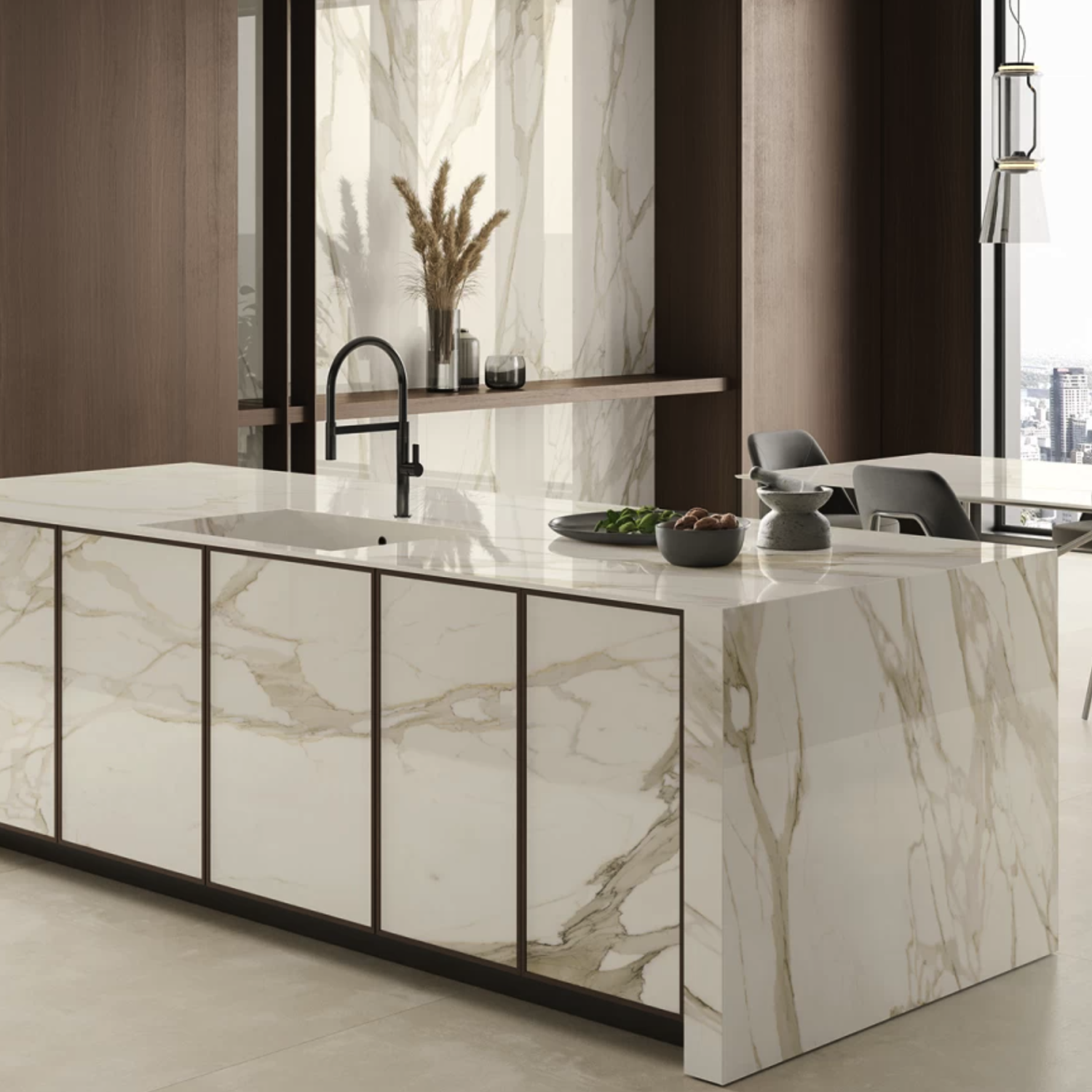 Contemporary kitchen featuring a Calacatta Borghini / Bernini marble island with an integrated sink and sleek dark faucet, complemented by minimalist decor. Rich brown cabinets, dried plants arranged in a vase, and expansive city views visible through large windows in the background.