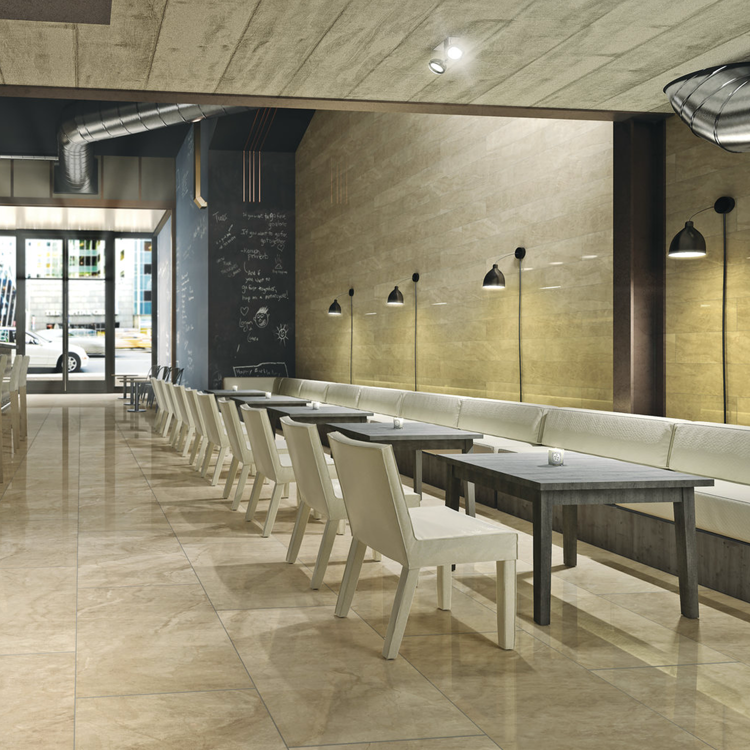 Modern cafe interior featuring Carrara Select - Carrara Paonazzo tiled floors, white cushioned chairs, long bench seating, black tables, wall-mounted lamps, and a chalkboard wall. Large windows display views of the city street outside.