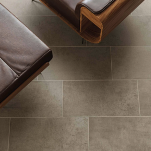 Cove - Taupe large, rectangular gray tiles arranged in a staggered pattern form the floor beneath brown leather furniture with wooden armrests.