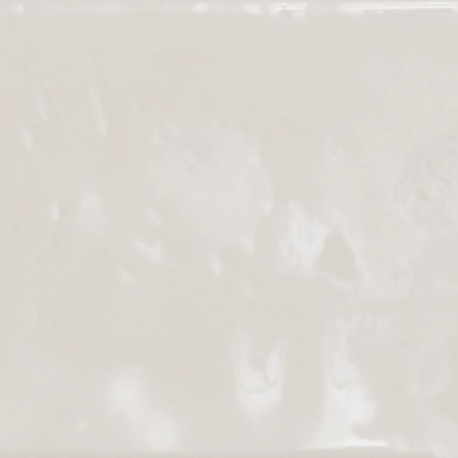 A close-up of the Cromia26 - Beige 1 ceramic tile surface reveals a smooth, glossy, off-white finish with subtle texture and gentle variations in shading.