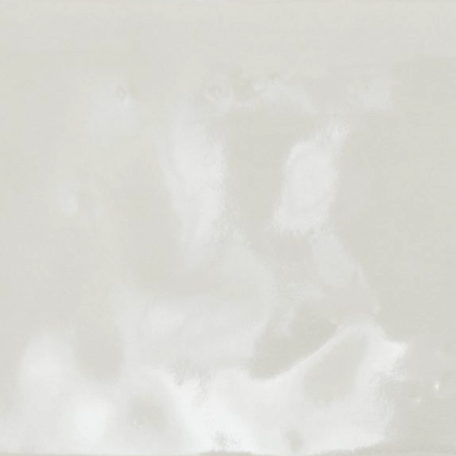 Cromia26 - Verde 1 is a glossy off-white ceramic tile featuring subtle reflections and an irregular surface texture.