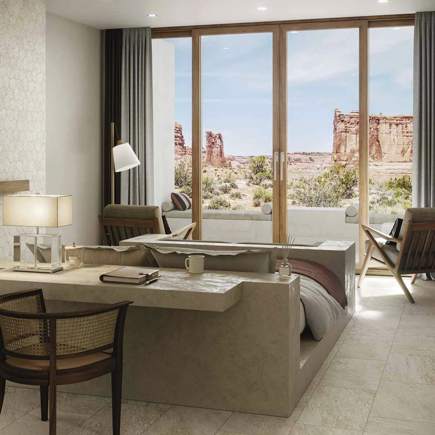 Modern hotel room featuring the Element - Ivory bed, complemented by a desk and chairs, with large glass doors opening to a patio that offers views of a rocky desert landscape beneath a blue sky.