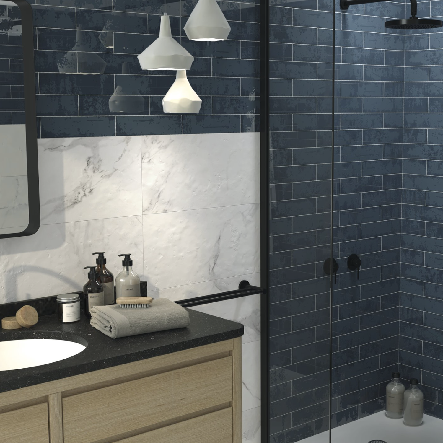 Modern bathroom featuring Grunge - Blue subway tile in the shower, white marble wall tiles, a wooden vanity with a black countertop, toiletries, folded towel, pendant lights, and a glass shower door.