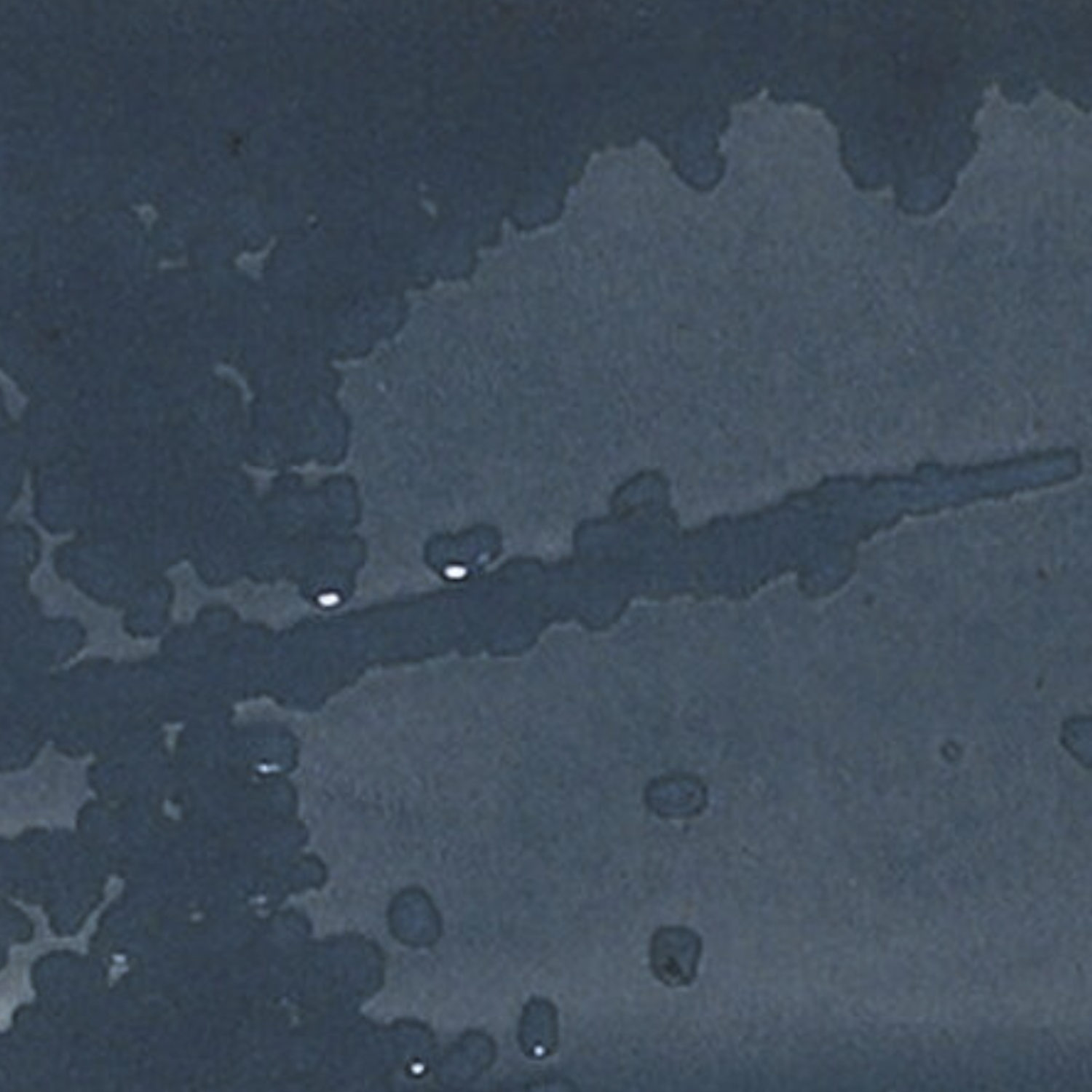 The Grunge - Blue features a dark blue surface accented with irregular lighter blue water stains and droplets scattered throughout, resembling wet spots or spills on a flat background.