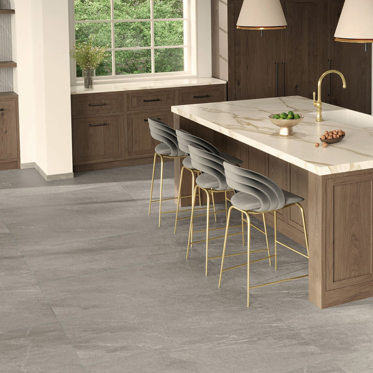Modern kitchen with wood cabinets, large window, Legacy Marblestone - Dove island countertop, four gray barstools with gold legs, and two pendant lights above the island. Bowl of green apples and plants are on the counter.