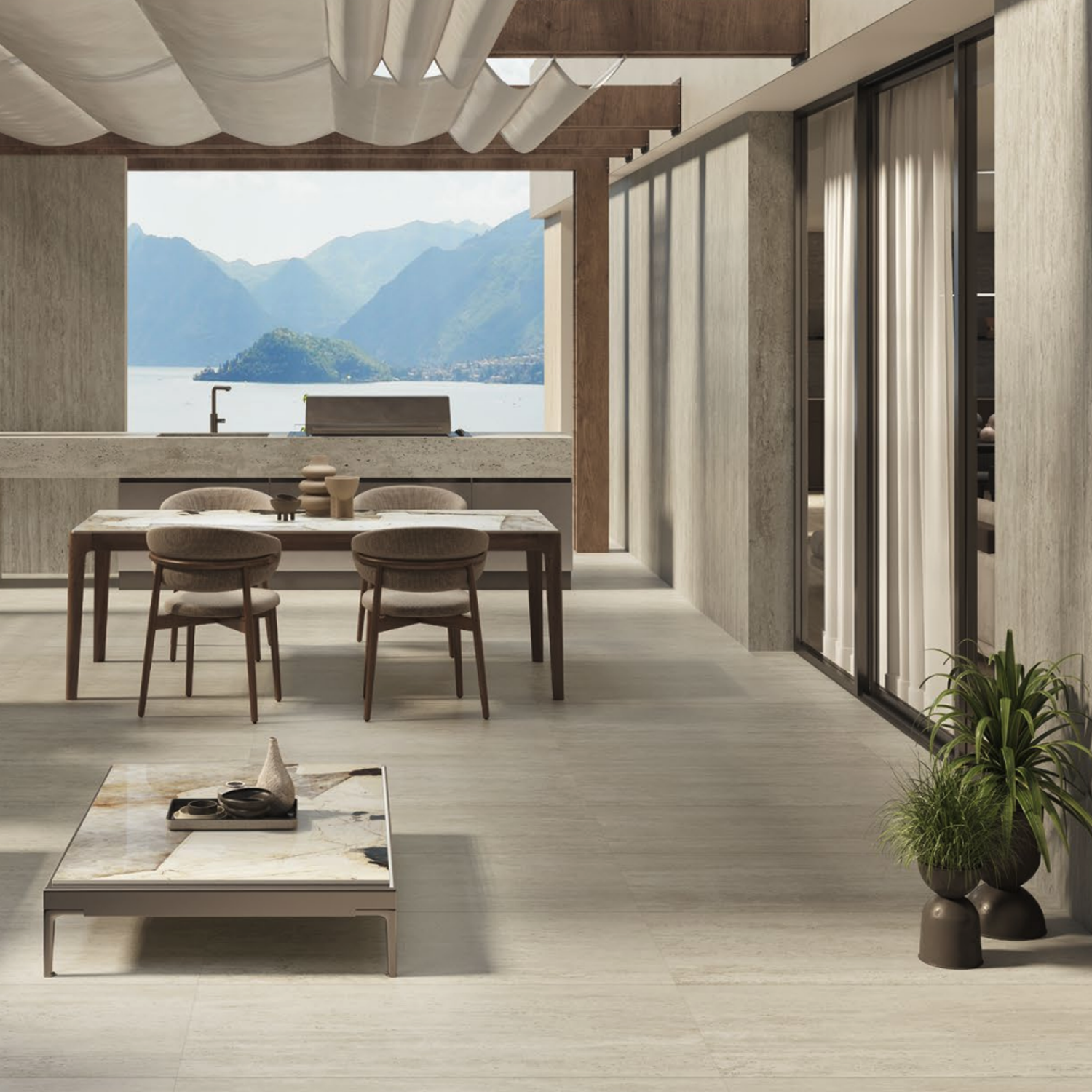 A contemporary open-plan living and dining space featuring neutral tones, expansive windows, a wooden dining table with chairs, potted plants, and stunning views of mountains and water in the background—all complemented by elegant Marvel Travertine - Pearl Vein Cut flooring.