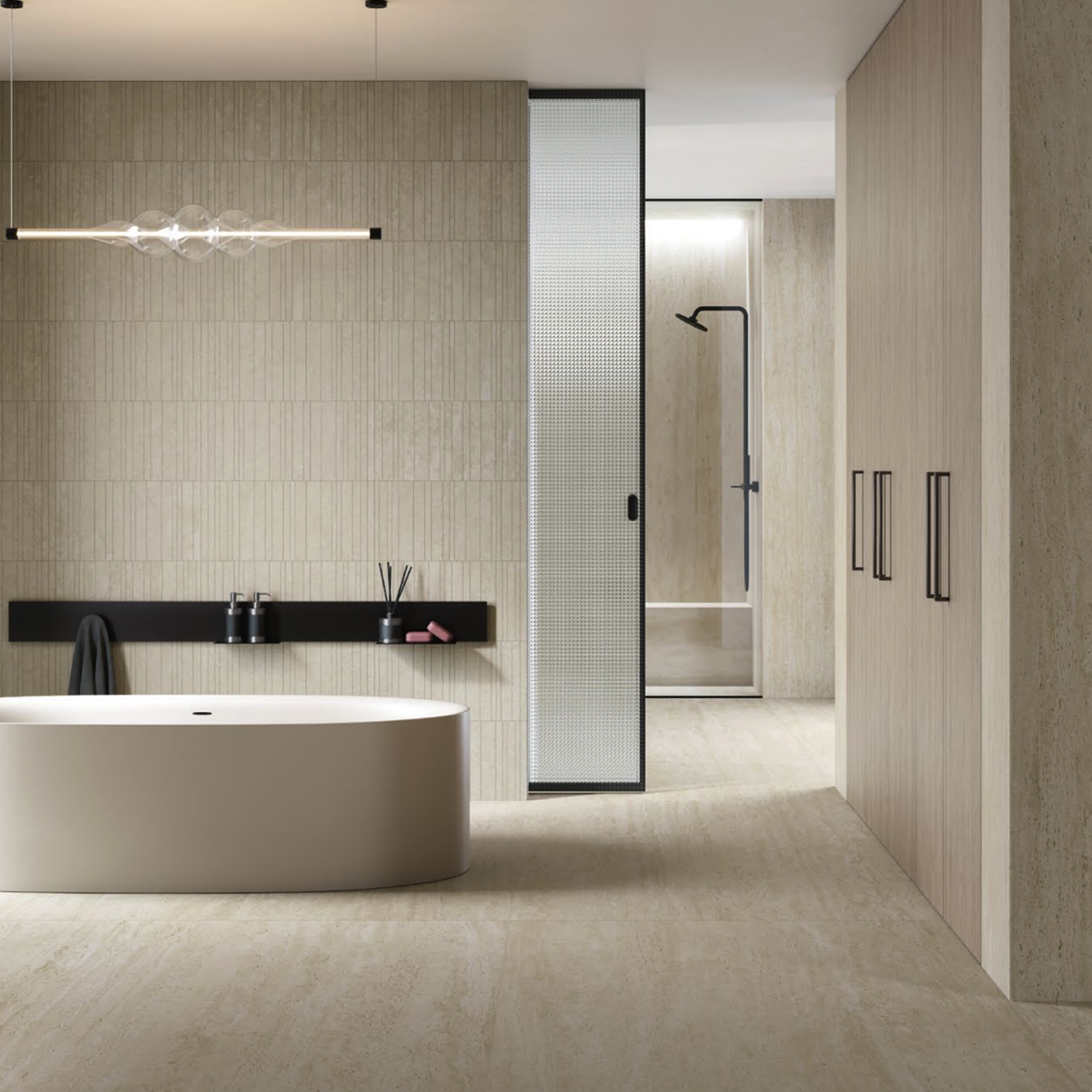 A minimalist bathroom features a freestanding oval tub, wall-mounted black shelf for toiletries, and a glass partition revealing a walk-in shower in the background. Marvel Travertine - Pearl Vein Cut tiles and sleek lines enhance the modern, serene atmosphere.