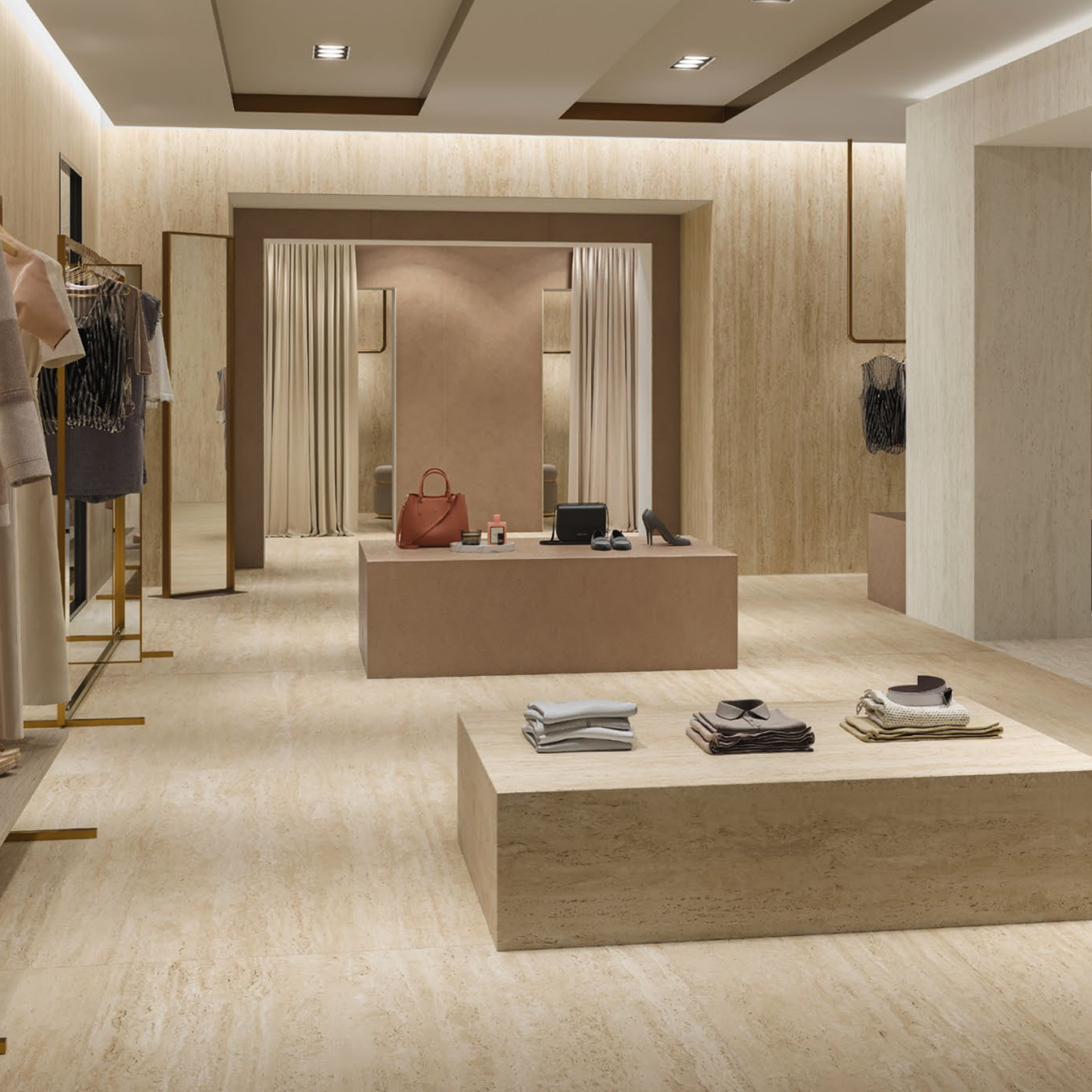 A modern boutique featuring Marvel Travertine - Sand Vein Cut on the floors and walls, with clothing displayed on racks and shelves, a display table showcasing folded clothes and accessories, and fitting rooms with curtained entrances in the background.
