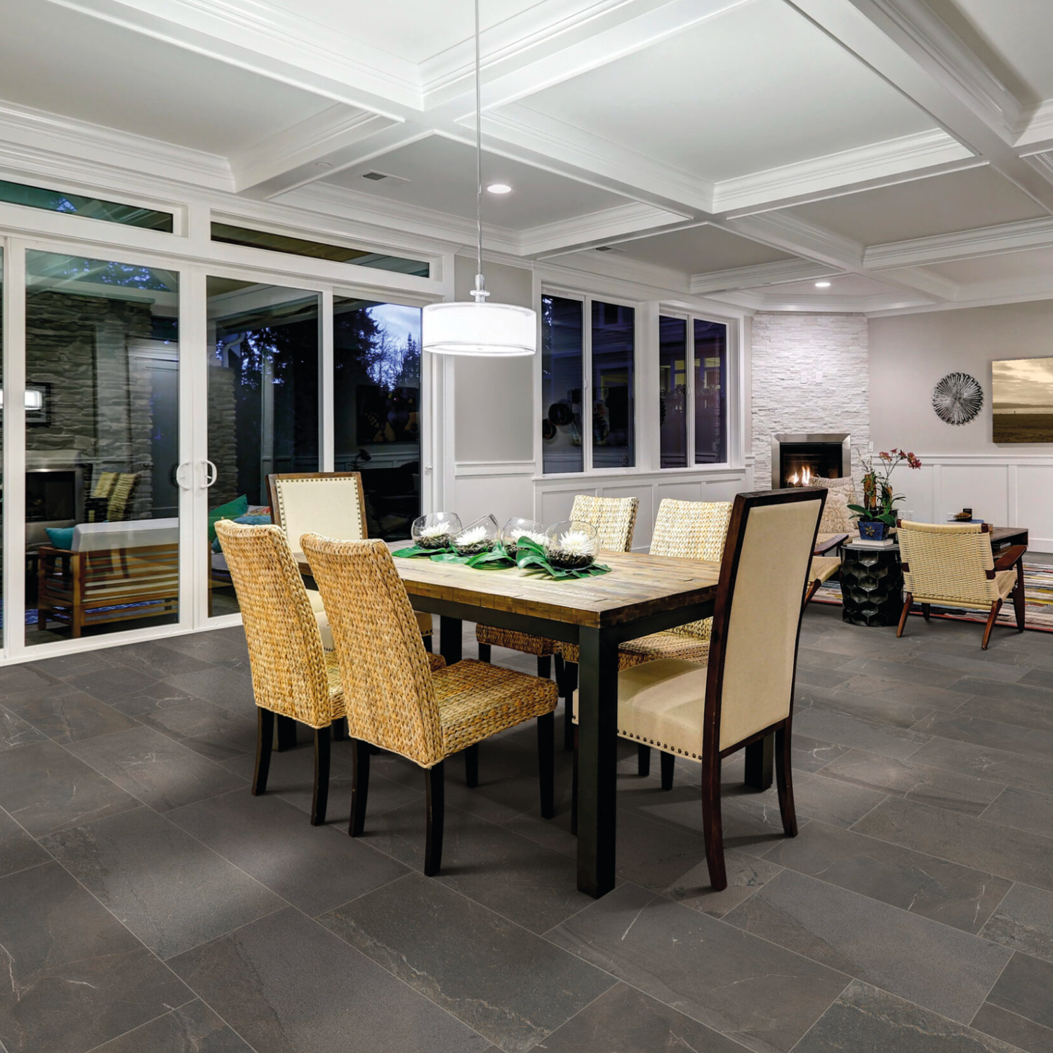 A contemporary dining room featuring a rectangular table, six chairs, expansive windows, sliding glass doors, a statement pendant light, and Modern Slate - Slate Taupe flooring with a view of a fireplace in the background.