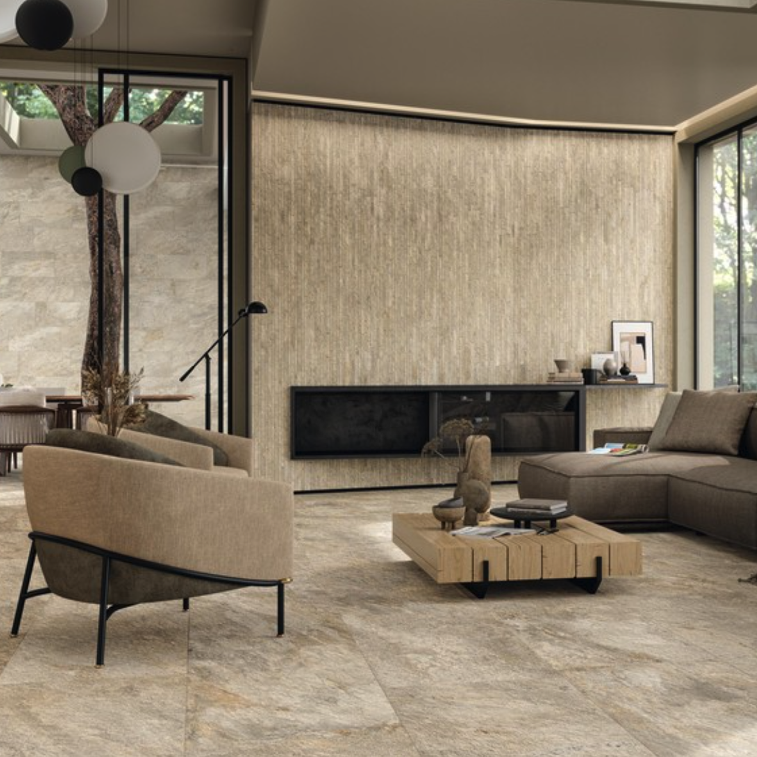Modern living room with Norde - Magnesio neutral stone tiles, beige armchairs, sectional sofa, minimalist decor, a wooden coffee table, art pieces, and large windows showing a tree outside.