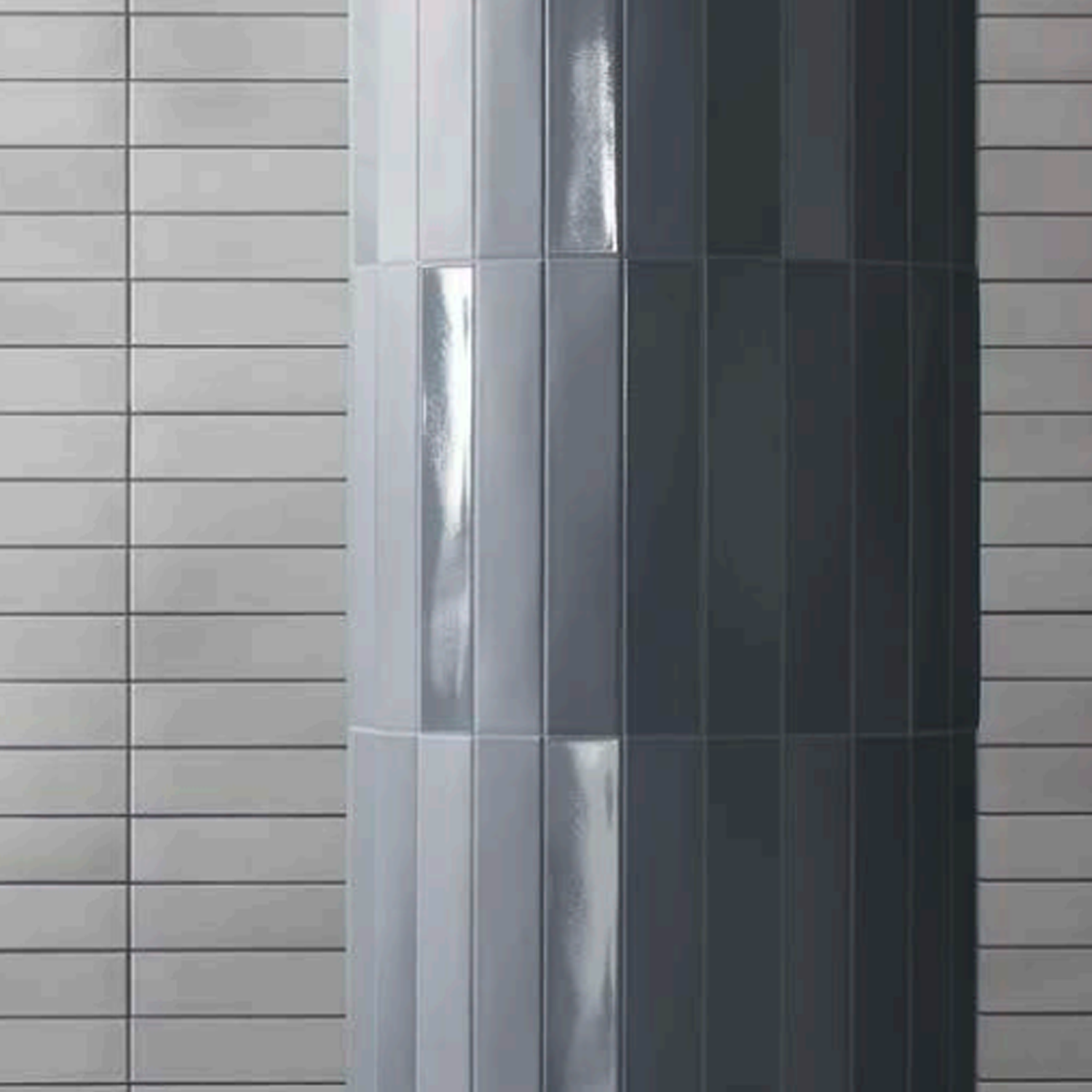 Pigmento - Azzuro rectangular tiles in a glossy blue finish cover a curved column, while matte light gray rectangular tiles are arranged horizontally on the adjacent flat wall in the background.