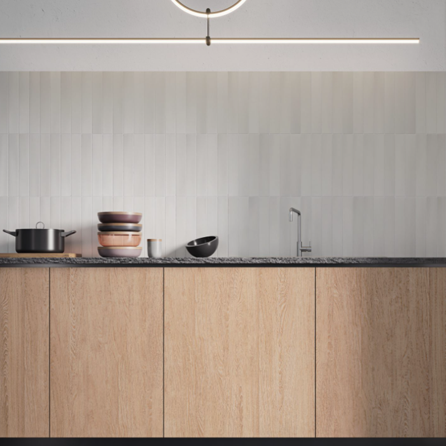Minimalist kitchen featuring light wood cabinets, a Pigmento - Grigio black countertop, stacked dishes, a pot, a bowl, built-in sink, and vertical white tile backsplash illuminated by a modern light fixture.