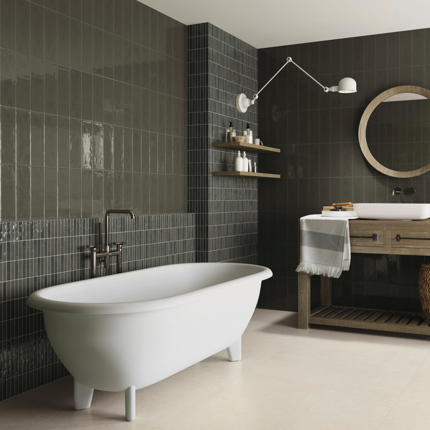 Modern bathroom featuring dark tiled walls, a white freestanding PIM PAM PUM - Pum Moss bathtub, wooden vanity with a round mirror, shelves with toiletries, and a wall-mounted lamp.