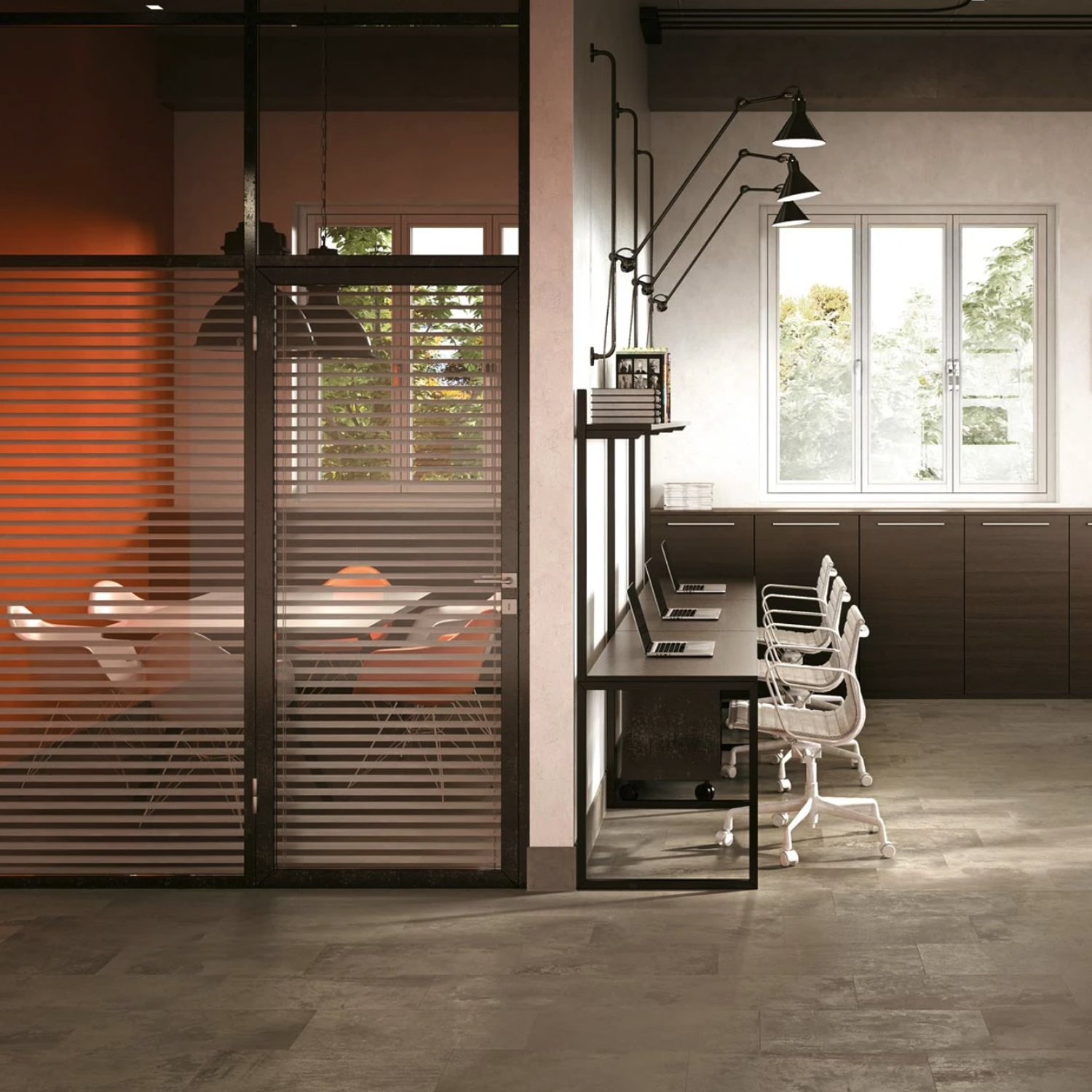 The Rift - Portland features a clean, minimalistic modern office space with a row of desks and chairs beside a window. On the left, a glass-walled conference room with orange accents and white chairs is visible behind horizontal blinds.
