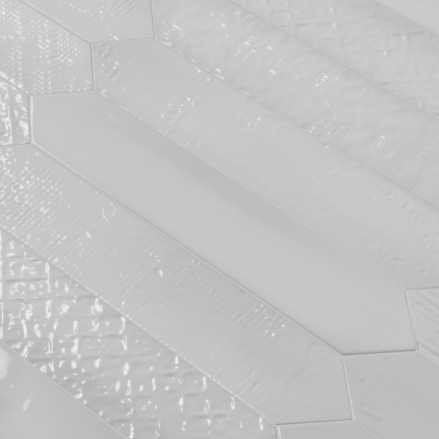 Close-up of Sfumature - Effetti Bianco tiles, featuring glossy, white, elongated hexagons arranged diagonally. The design alternates between smooth-finished tiles and those with a textured, rippled surface, creating a dynamic pattern of contrasting textures.