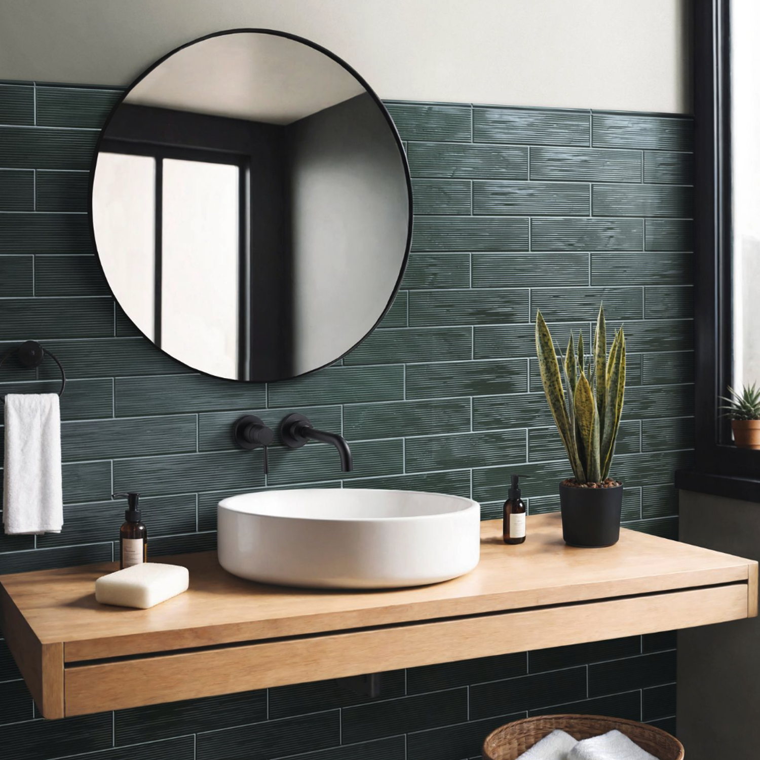 A modern bathroom featuring dark green tile, a round mirror, a light wood floating vanity, vessel sink, potted plants by the window, toiletries, and the Swing - Musk soap bar.