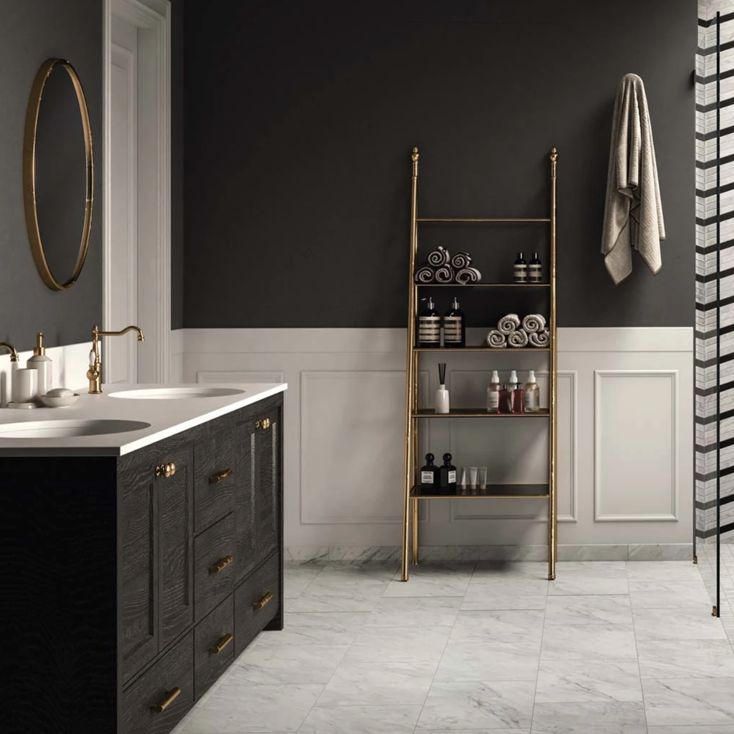 Modern bathroom featuring the Trilogy - Carrara Classic marble floor, complemented by a black vanity, round mirror, gold fixtures, towel on the wall, and a gold shelving unit displaying toiletries and rolled towels against dark and white paneled walls.