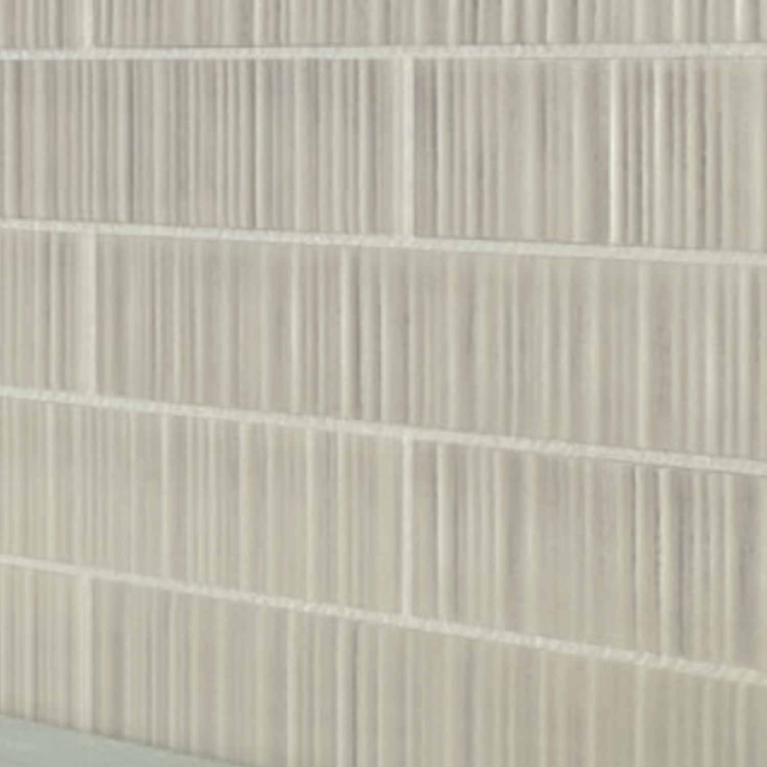 Close-up of a wall with rectangular Vibrant - Beige tiles featuring a vertical striped texture in a light beige color. The tiles are arranged in a horizontal pattern.