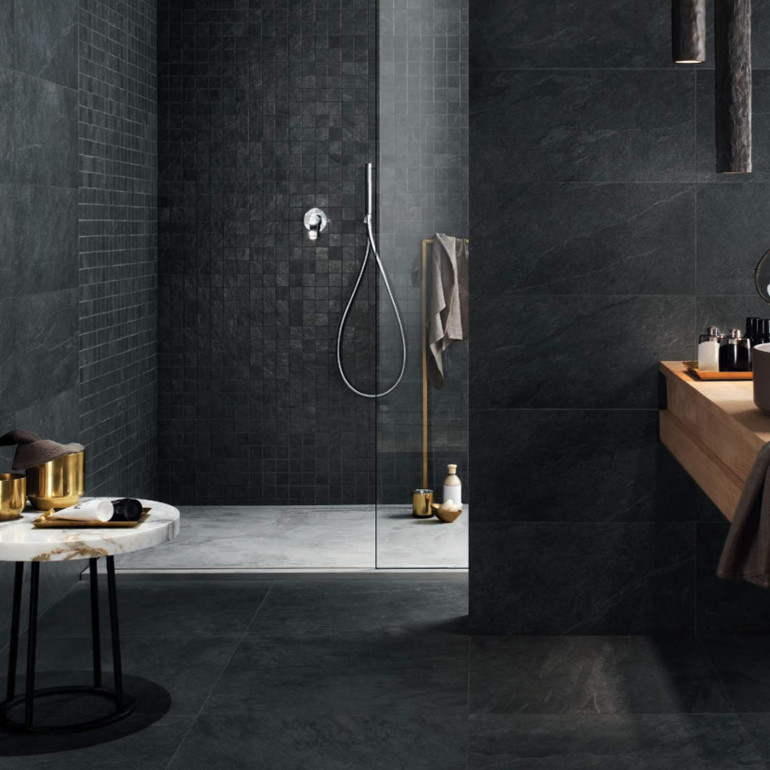 Certainly! Here’s your rewritten sentence using the product name: Modern bathroom featuring the Waterfall - Dark Flow, complemented by dark tiles, a glass shower, wooden sink counter, marble side table, towel rack, and bath products arranged neatly. The space boasts a sleek and minimalistic design with a moody atmosphere.