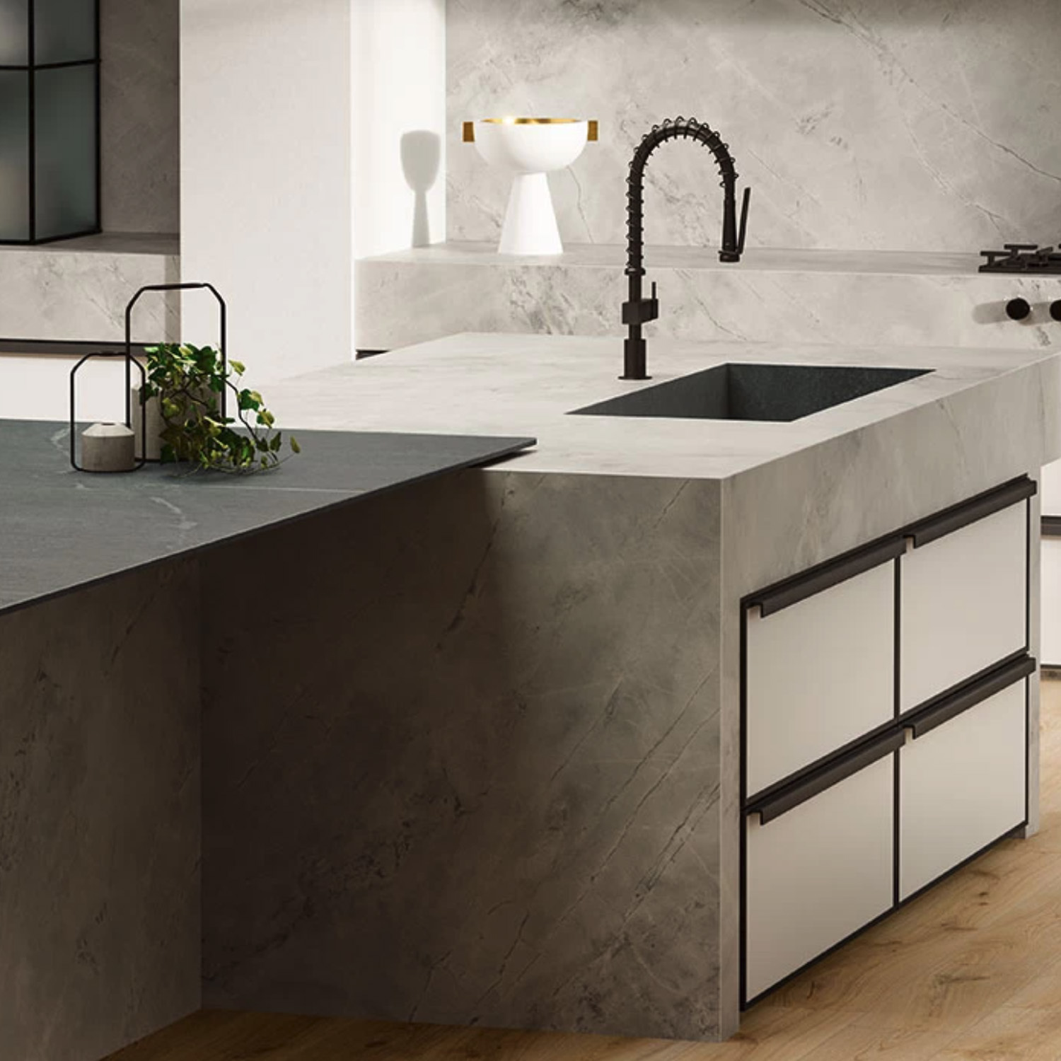 Modern kitchen with a White Cloud marble island featuring a black sink, tall black faucet, and minimalist white drawers. A plant sits on the countertop next to the sink. Marble backsplash and light wood flooring are visible.