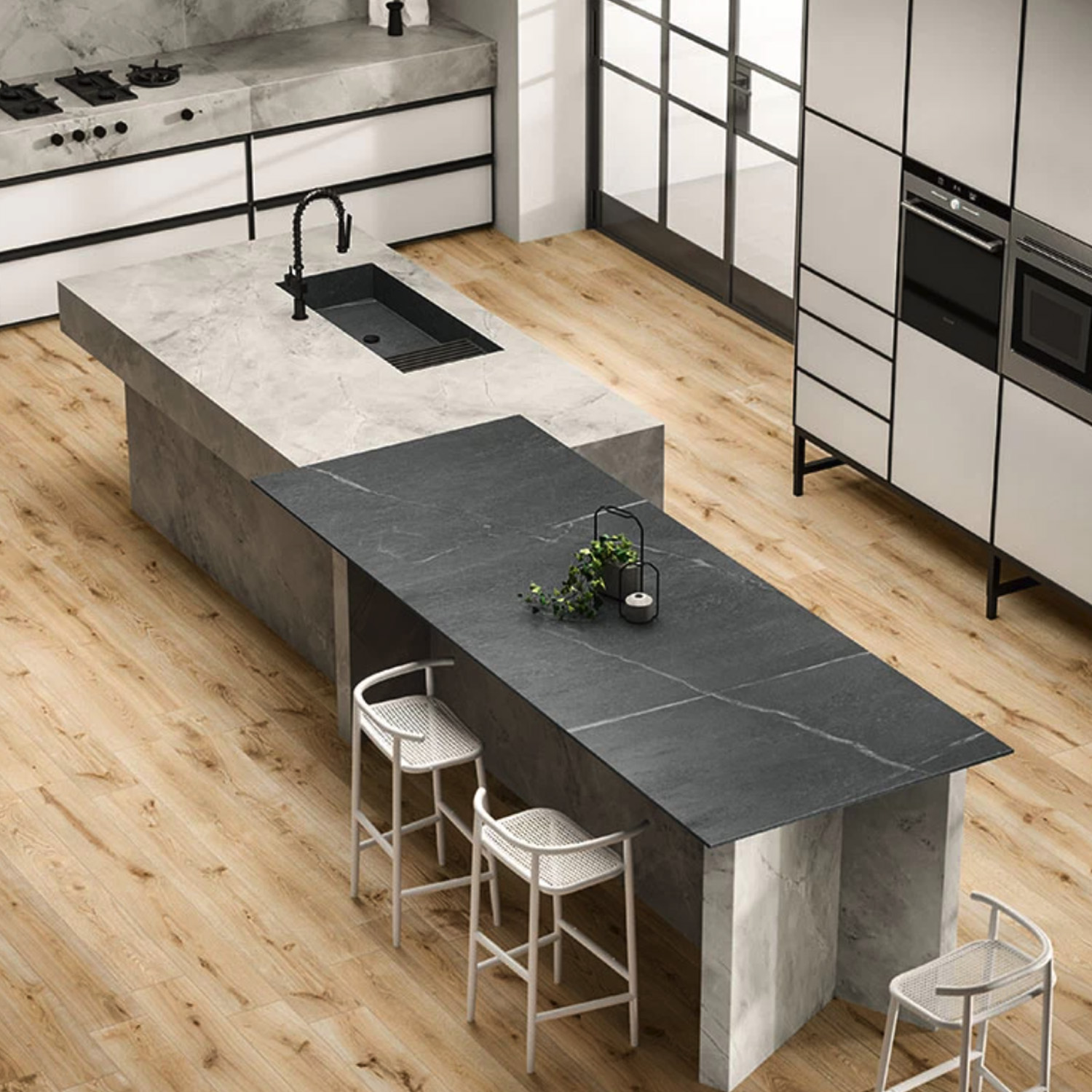 Modern kitchen featuring the White Cloud marble island, a sleek black sink, an extended black tabletop, three white barstools, light wood floors, and white cabinetry with built-in appliances. Large windows in the background fill the space with natural light.