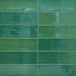 Zellige - Green subway tiles create a glossy backsplash in the kitchen, complemented by a countertop displaying stacked white bowls, a striped towel, a small wooden bowl, and a potted plant with round leaves.
