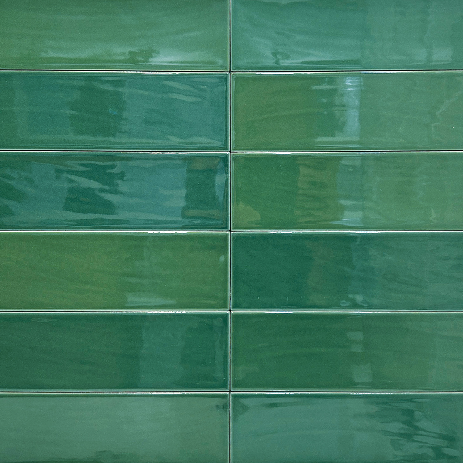 Zellige - Green rectangular ceramic tiles, arranged in a horizontal brick pattern, feature varying green shades and glossy finishes that beautifully reflect light.