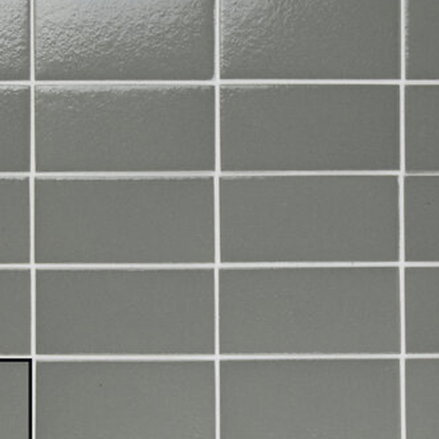 Arka - Arka Steel ceramic tiles are arranged in a grid pattern with white grout lines. The image features a close-up of the corner of the tiled surface, highlighting part of a black border in the lower left.
