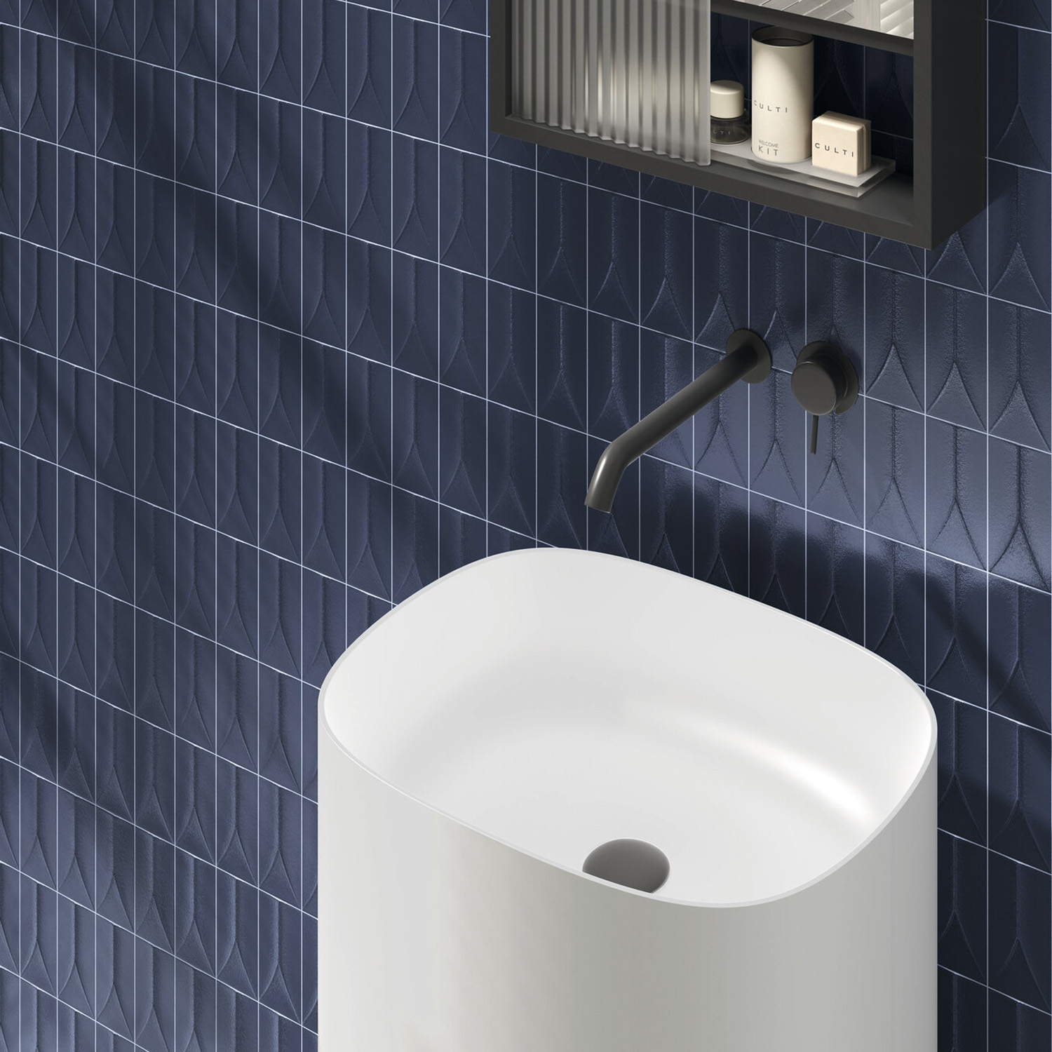 Arka - Forma Blue sink with a sleek black wall-mounted faucet, set against a textured blue tiled wall. Above, a shelf holds various bathroom items, creating a clean and minimalist scene.