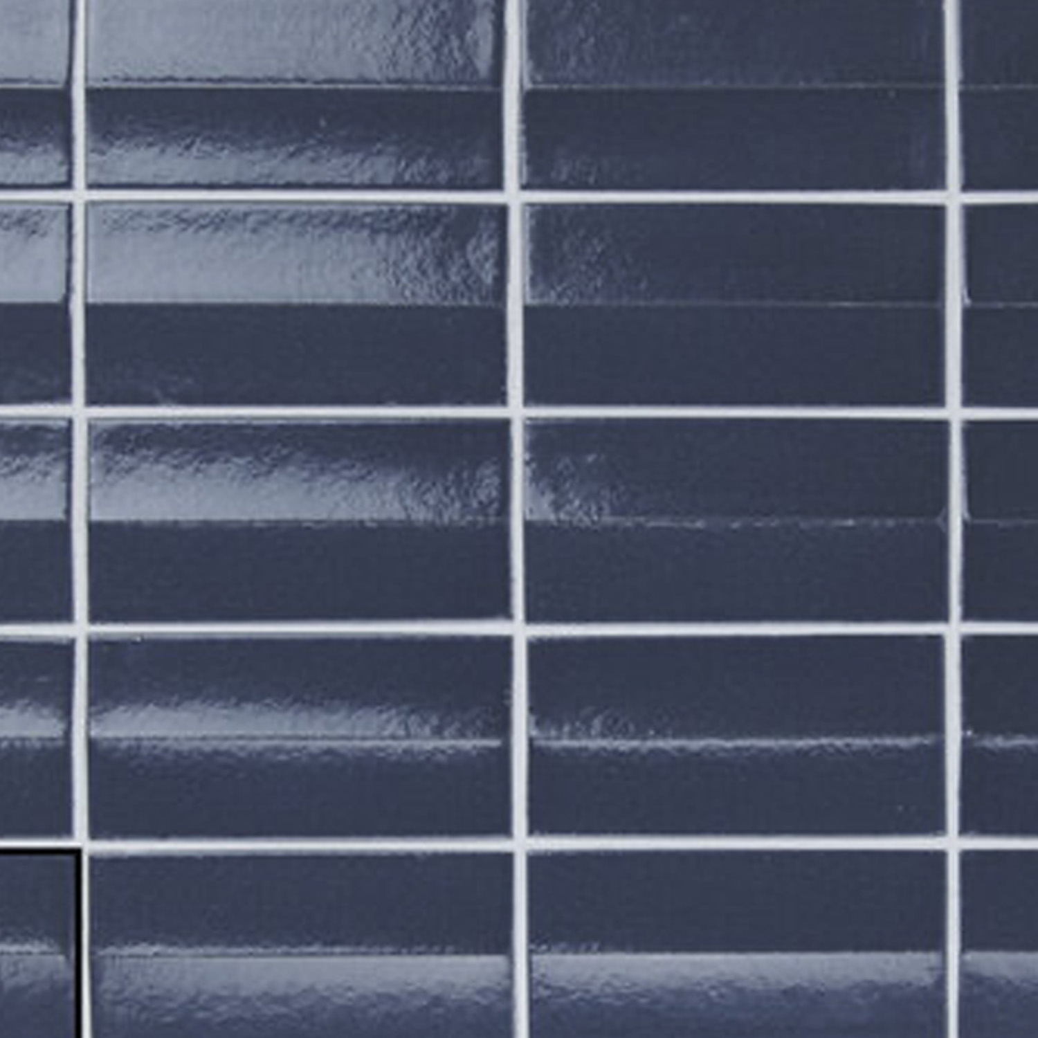 Arka - Ona Blue glossy rectangular ceramic tiles in navy are arranged in a grid pattern with white grout; one corner tile is slightly misaligned.