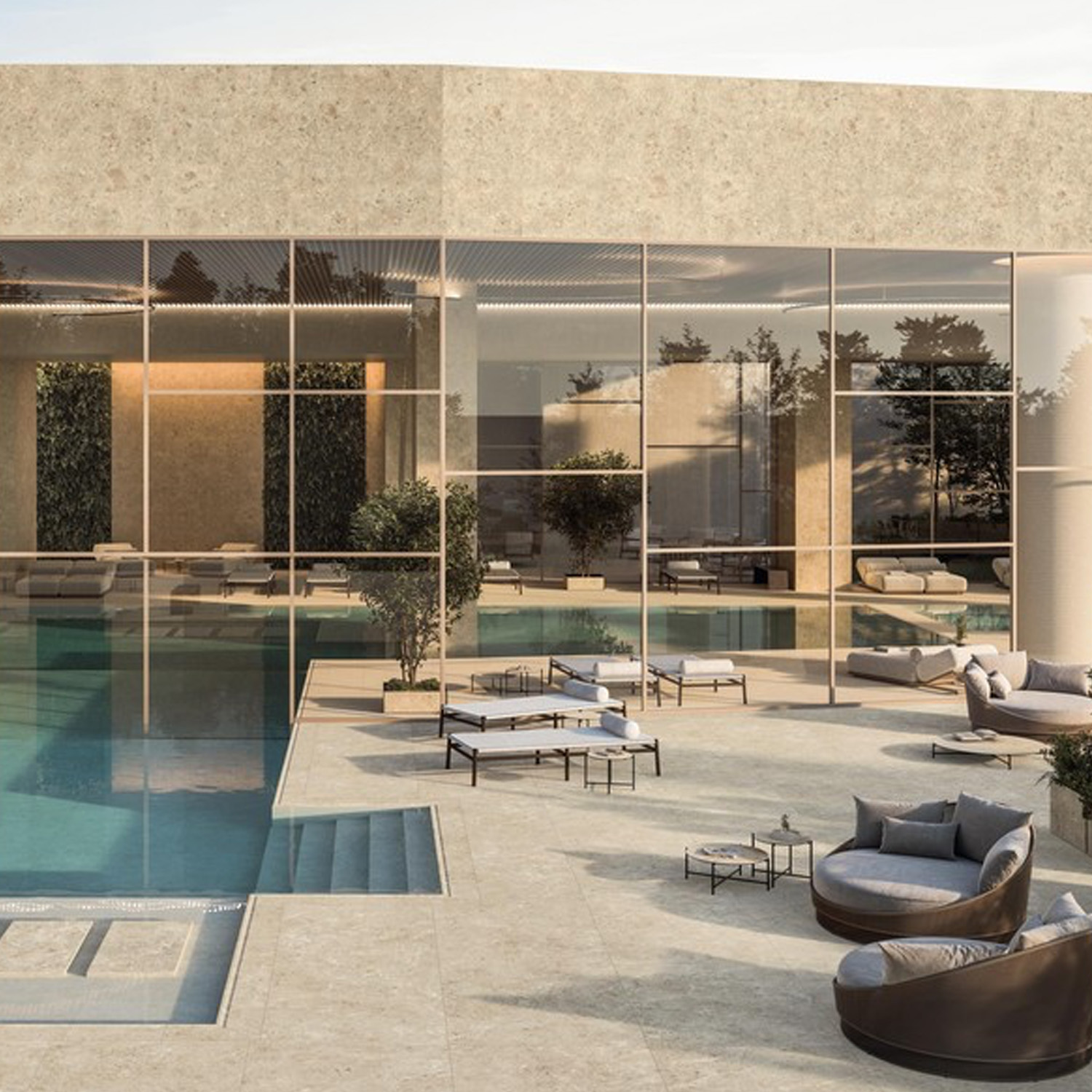 Modern outdoor pool area featuring the Nyra - Hay collection, with beige stone flooring, lounge chairs, circular sofas, tables, and expansive glass windows reflecting trees and sky; a minimalist and elegant design.