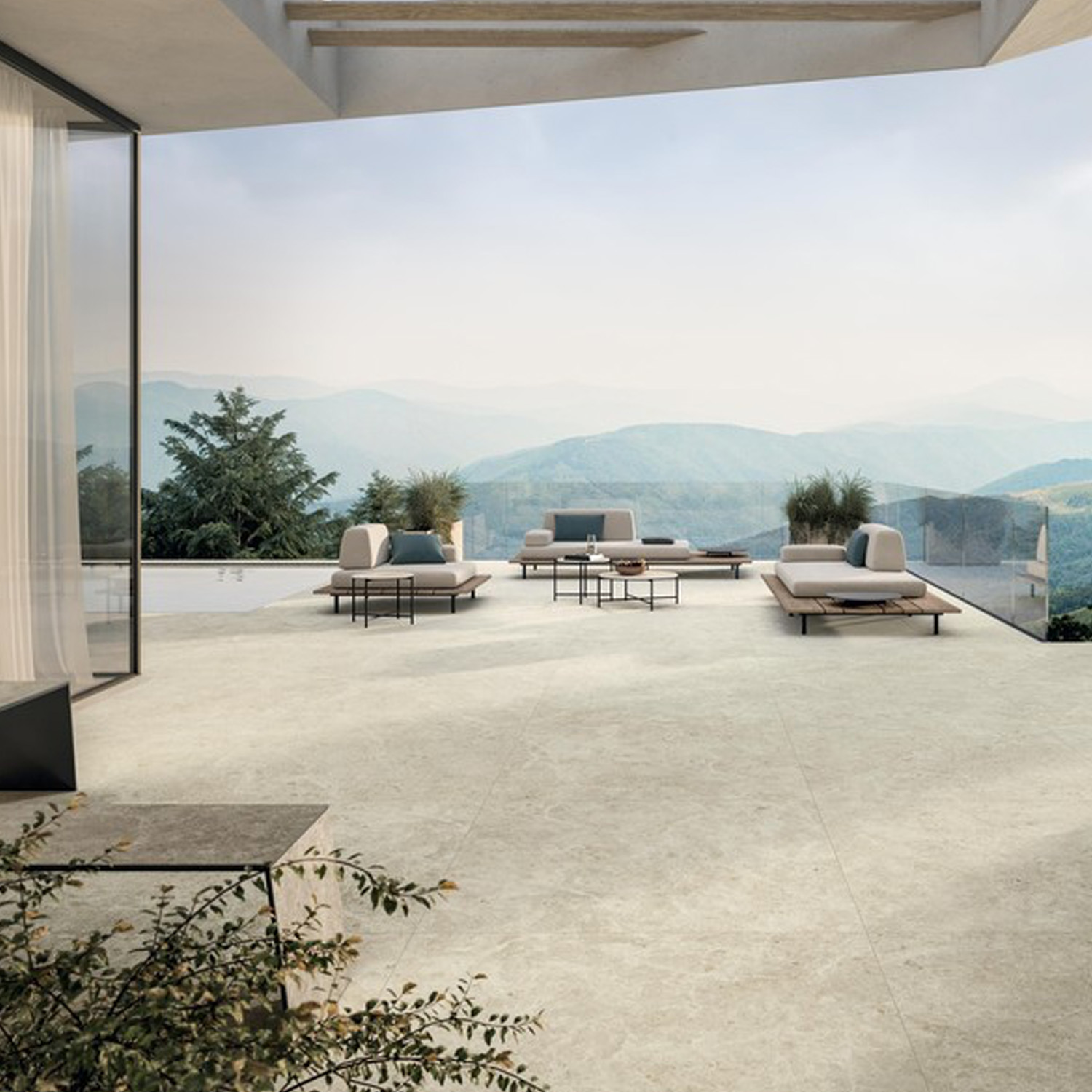 Modern terrace featuring Nyra - Star light stone flooring, outdoor lounge chairs, potted plants, glass railing, and a scenic mountain view under a cloudy sky.