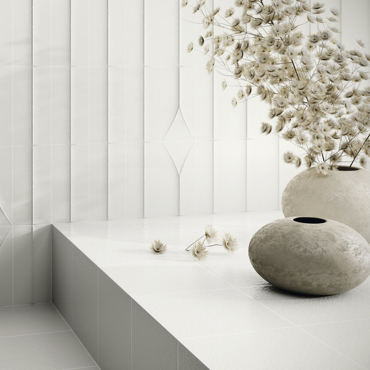 Minimalist scene showcasing Arka - Forma White tiles, their textured white surface complemented by two round stone vases and delicate dried white flowers. The background highlights vertical rectangular and diamond patterns, creating a modern, serene aesthetic.