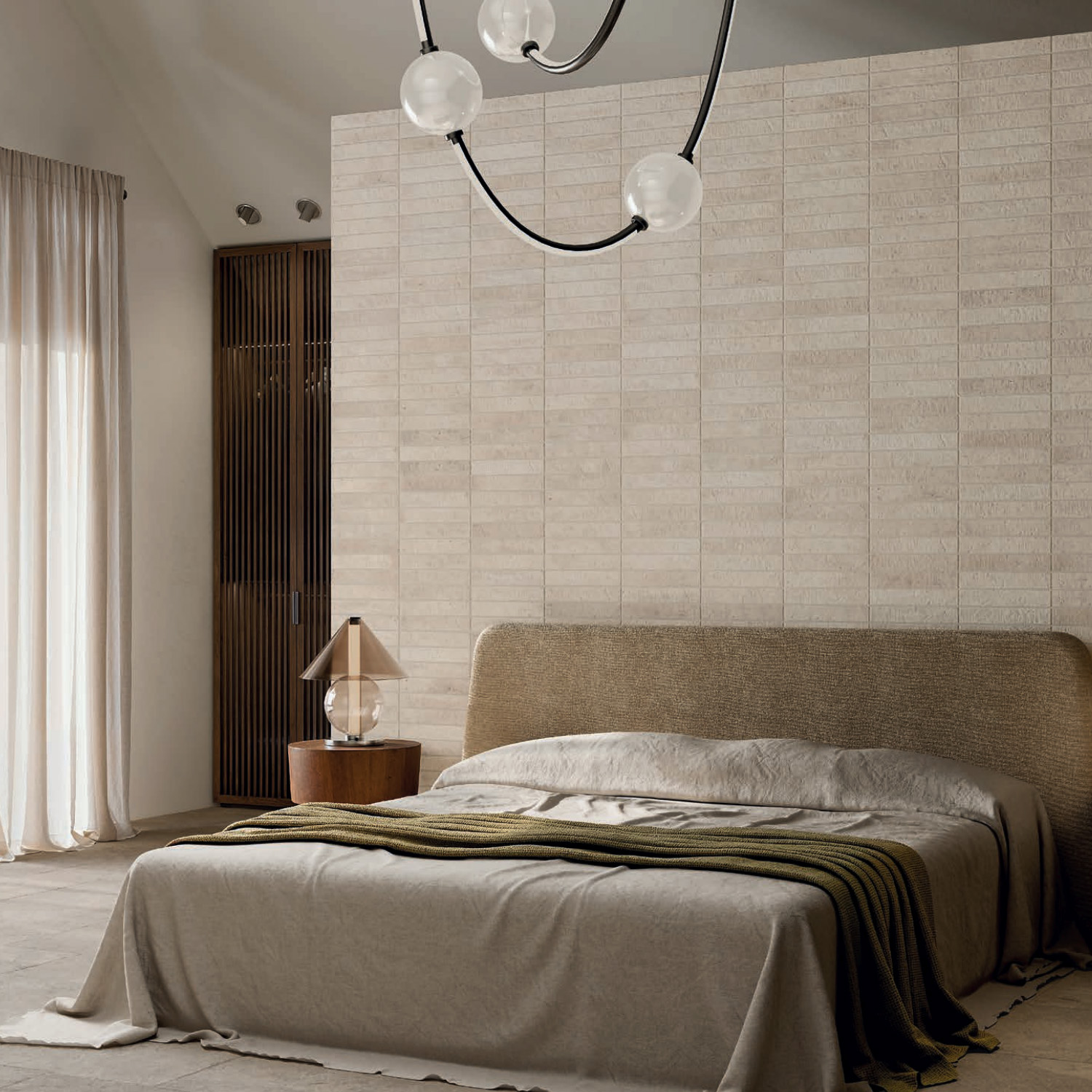 A modern bedroom featuring the Tyrrhenia - Bone bed, a textured wall, a glass lamp atop a round wooden nightstand, floor-to-ceiling curtains, and a black chandelier with globe bulbs suspended from the ceiling.