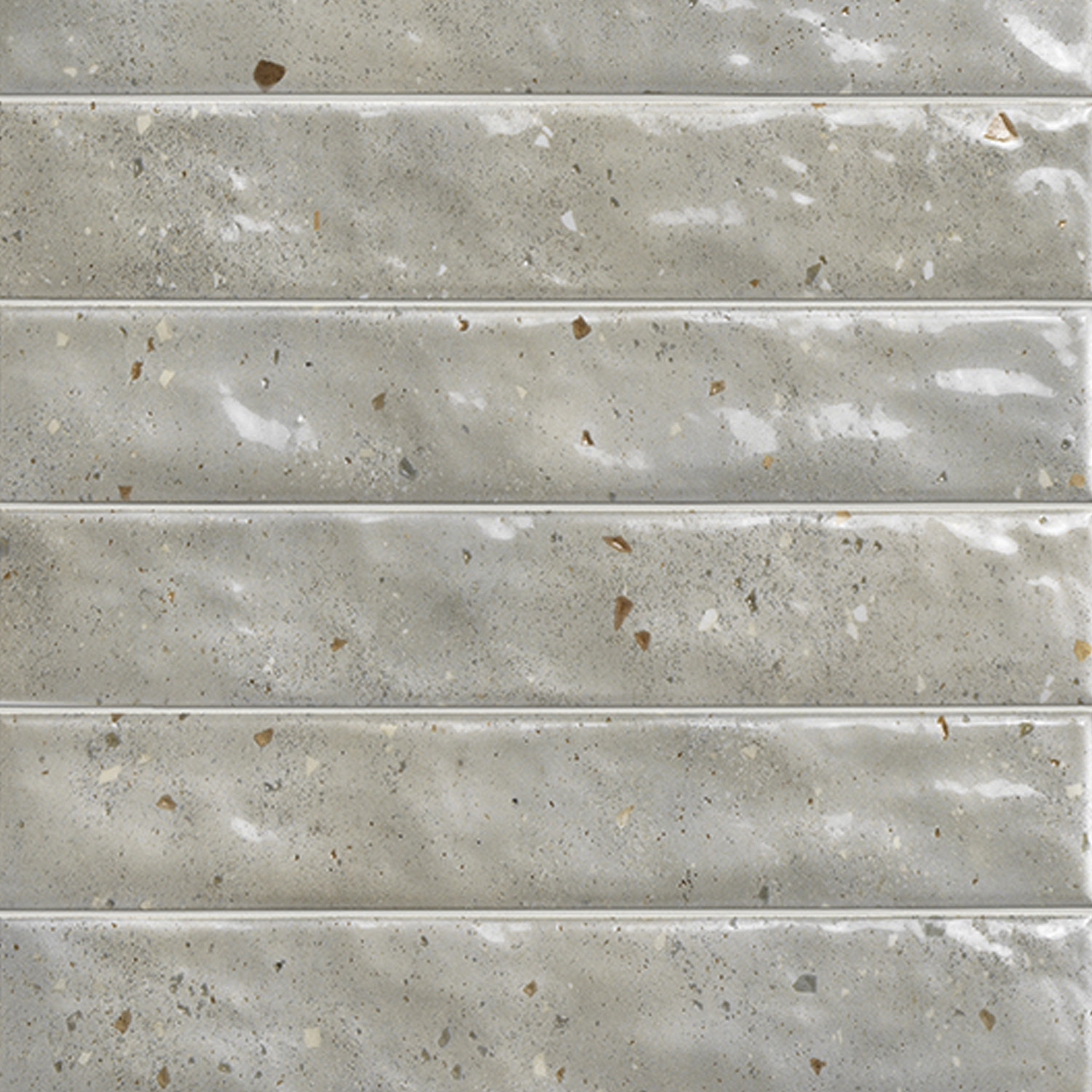 Rectangular Via Del Sale - Mud tiles in a light gray color with a glossy finish, featuring faint speckles and small brownish flecks. Arranged horizontally with visible grout lines, the tiles have a subtly uneven, textured surface.